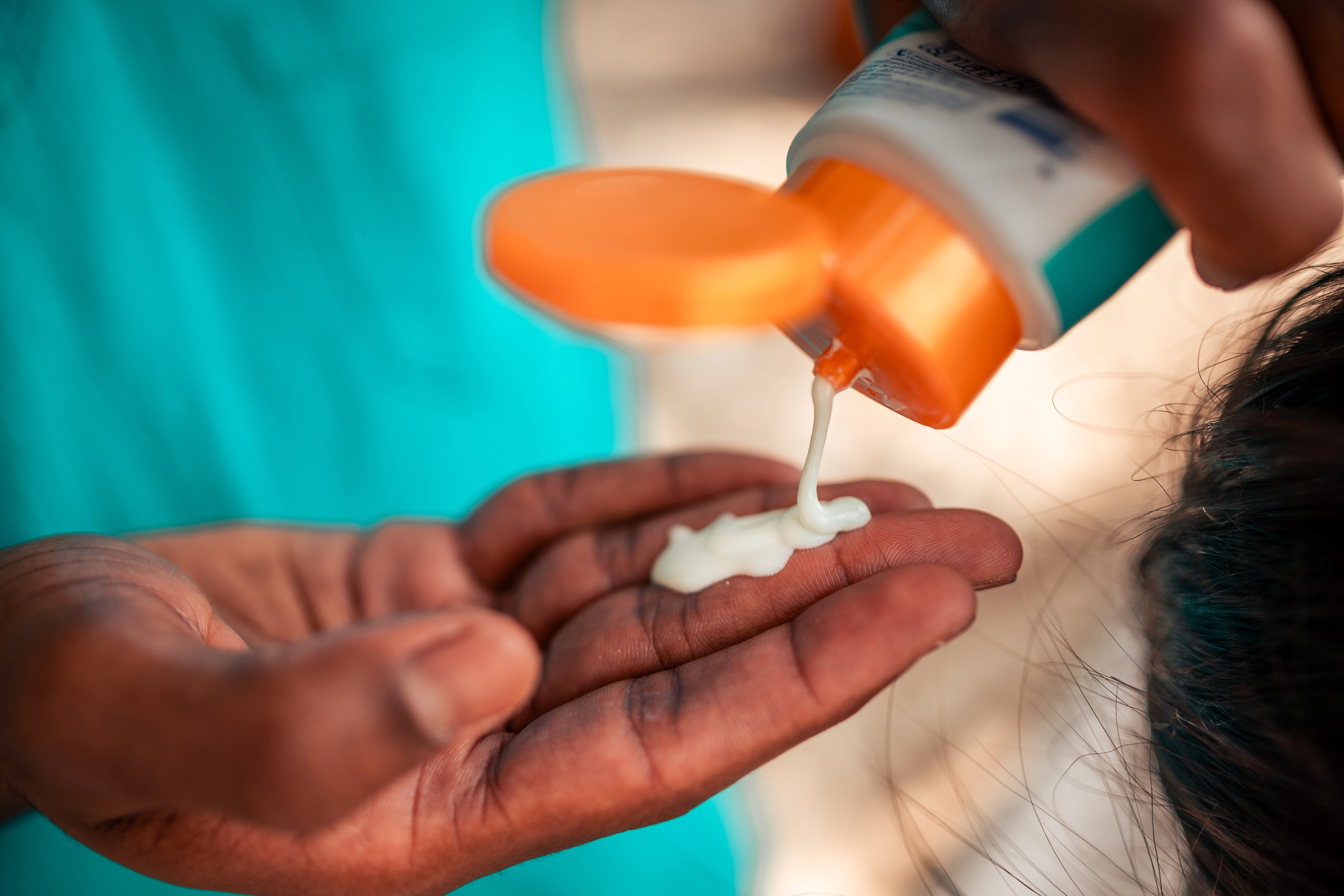Sunscreen pours from a squeeze tube into an open hand