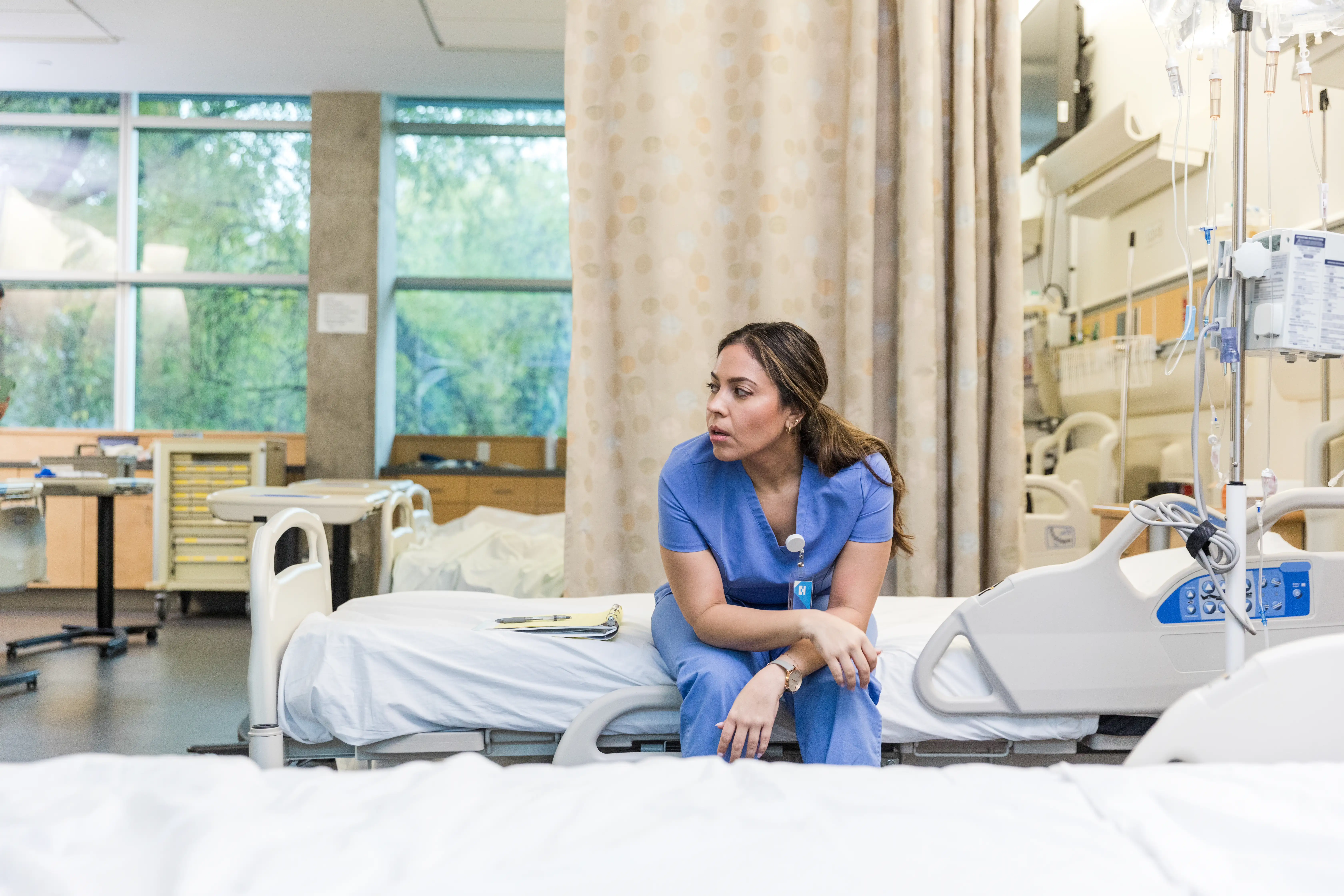 A young female doctor sits down to take a breather on an empty bed