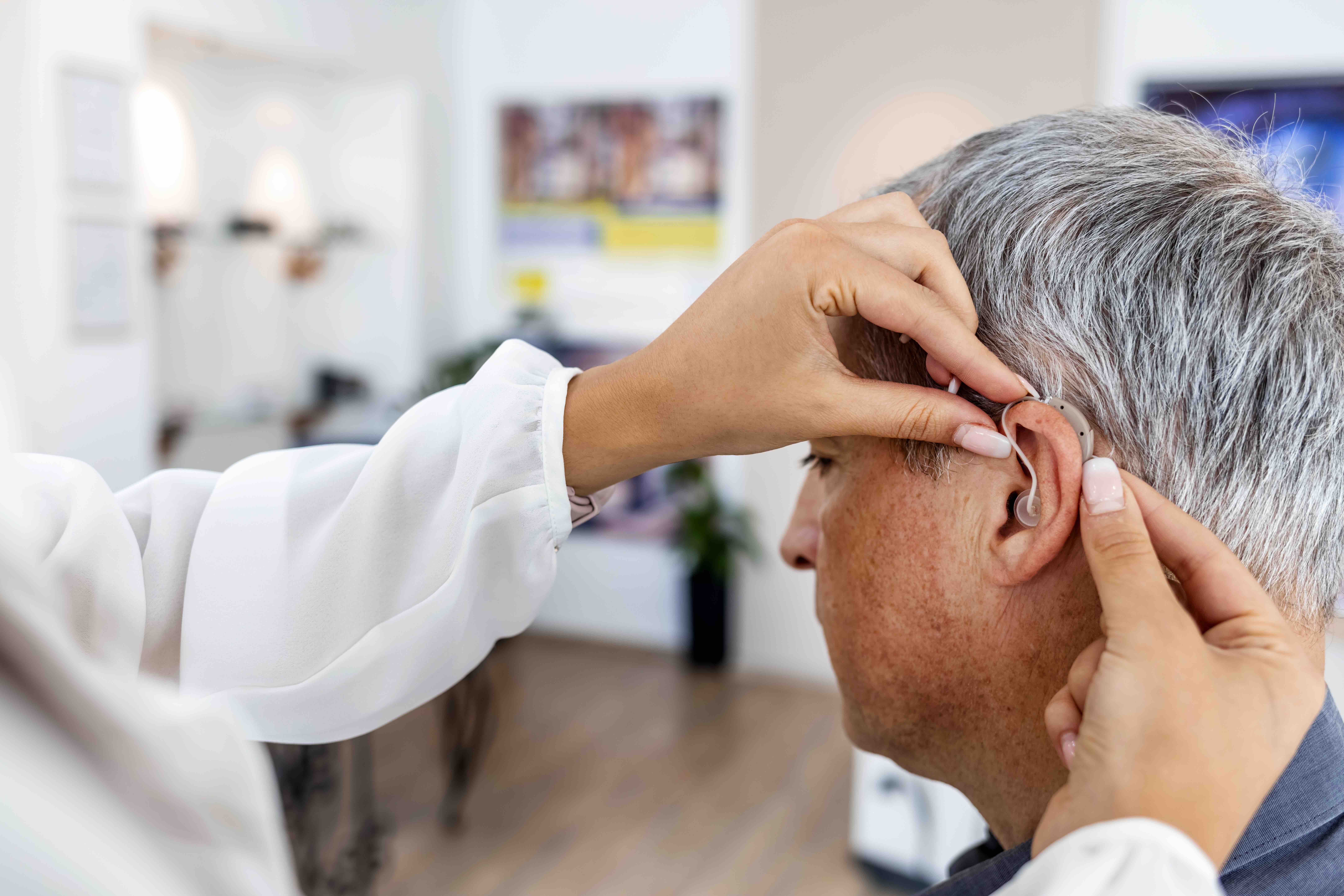 An older man being fitted with a hearing aid