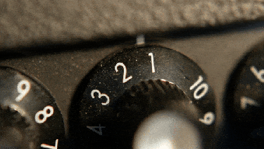 A hand turning up the volume on an amp