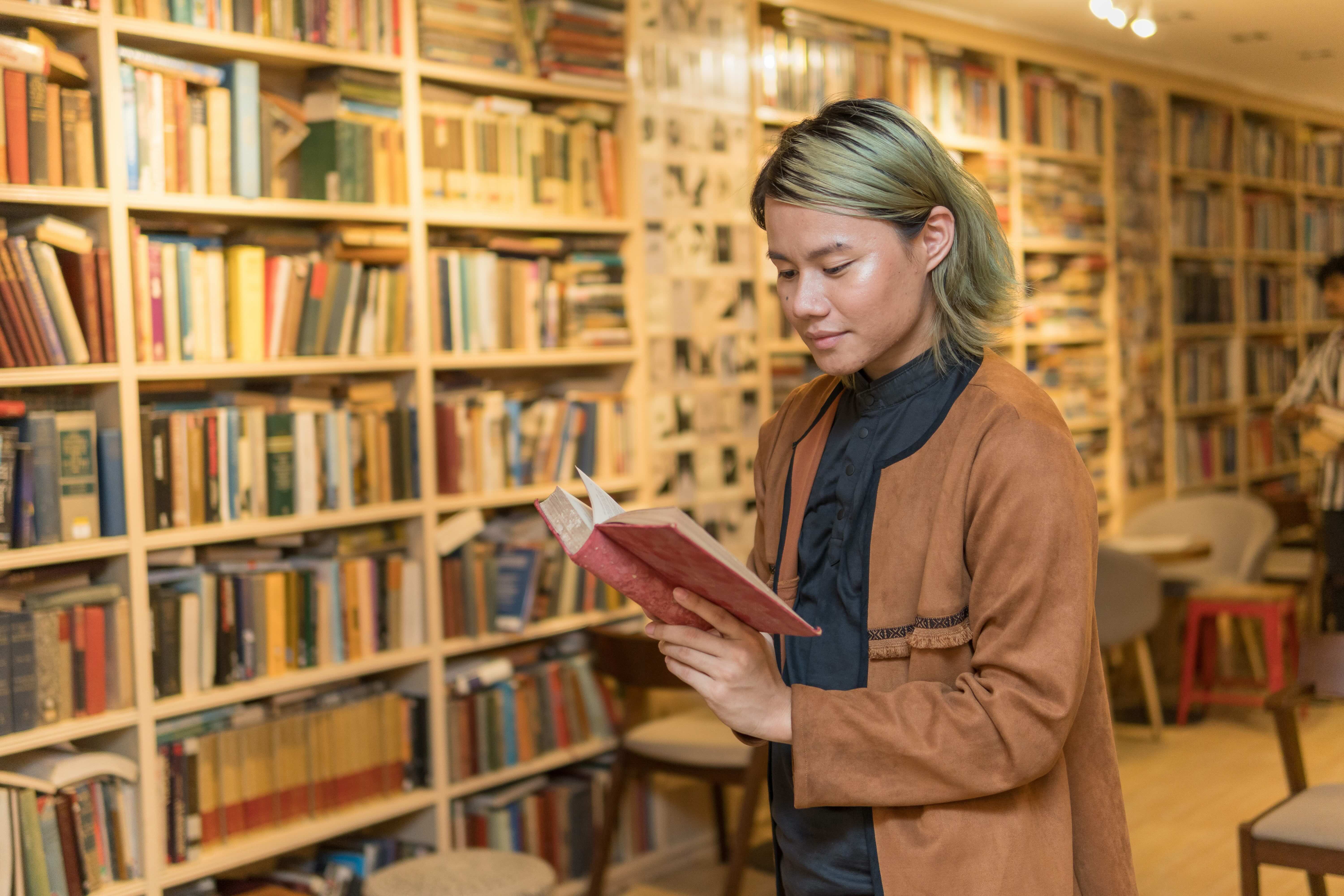 Young non binary person reading in library