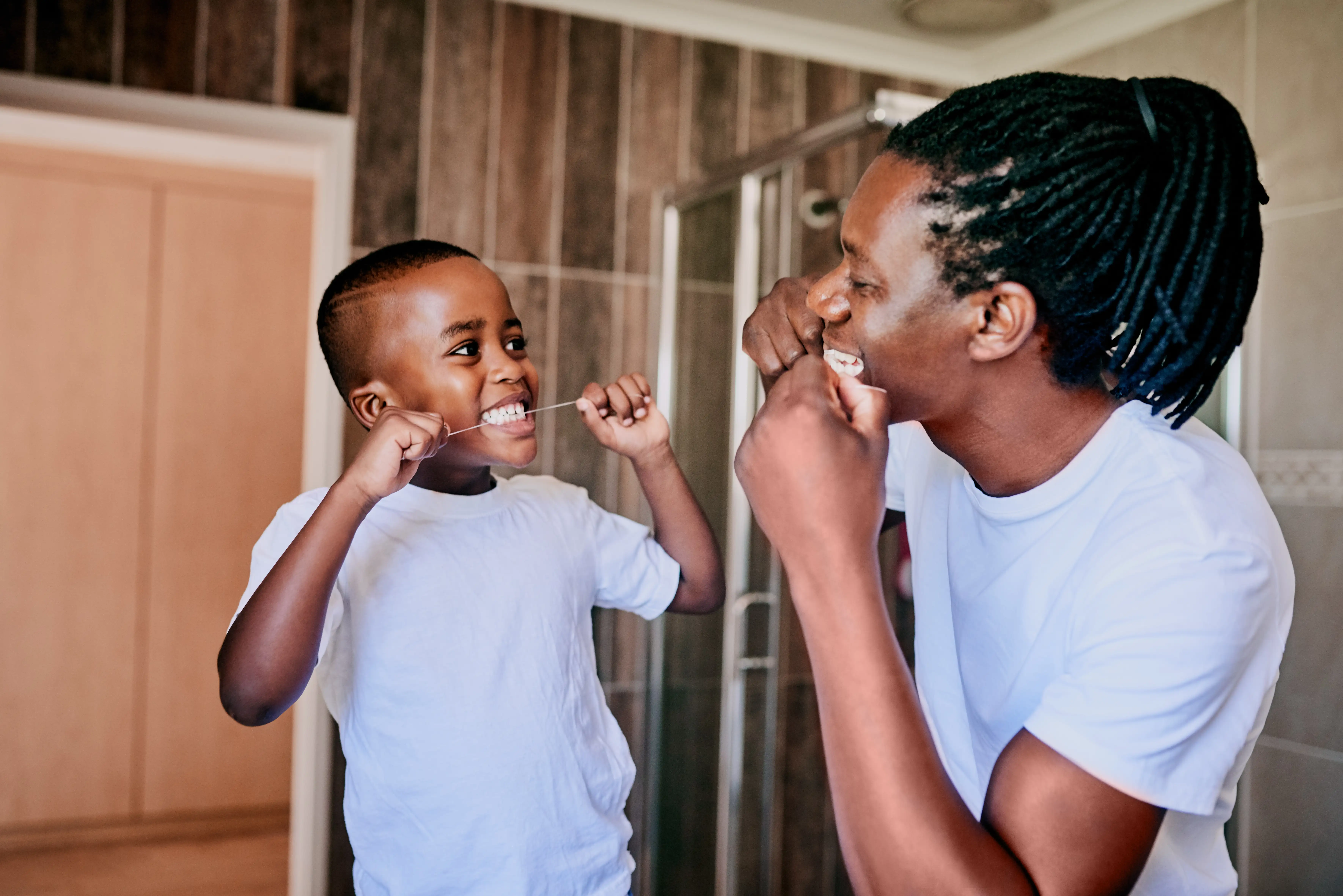 Father and son flossing teeth in the bathroom