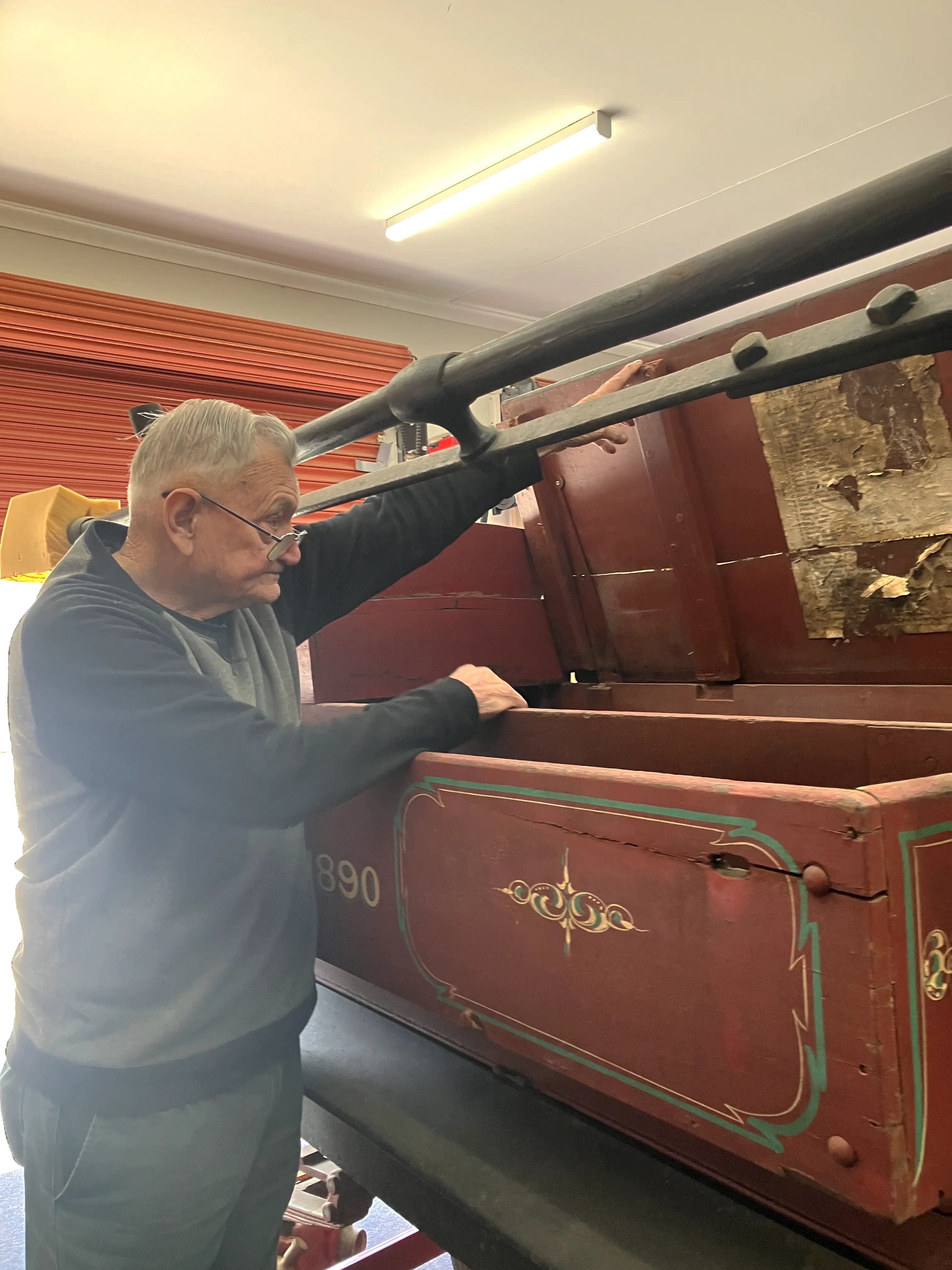 A man holds a large, decaying red chest open, where the fire brigade previously kept necessary equipment