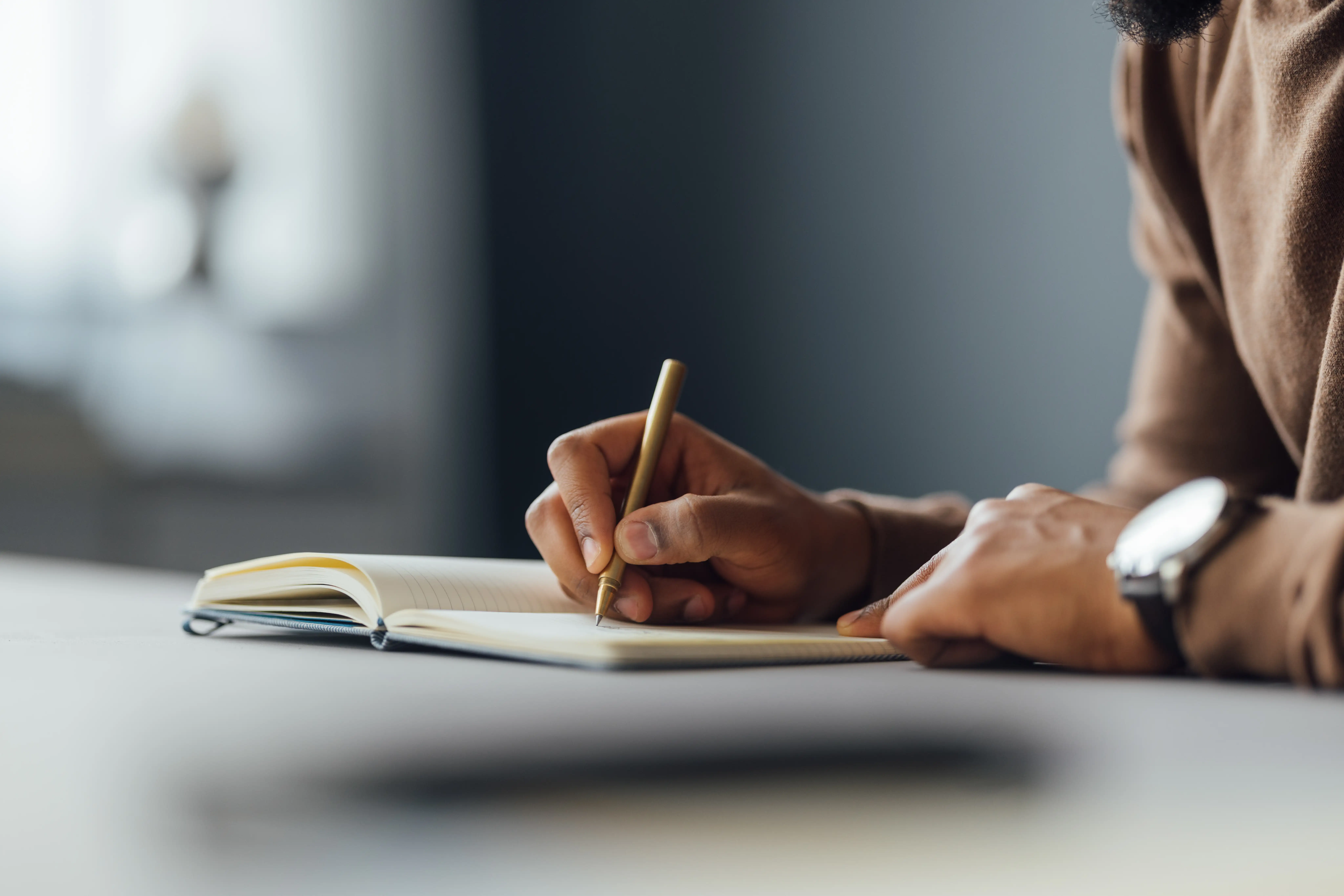 A person writing in a notebook using a pencil