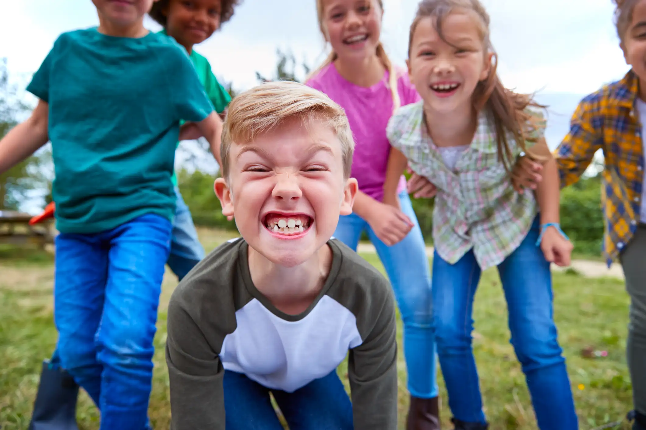 A big group of kids with one in particular grinning at the camera