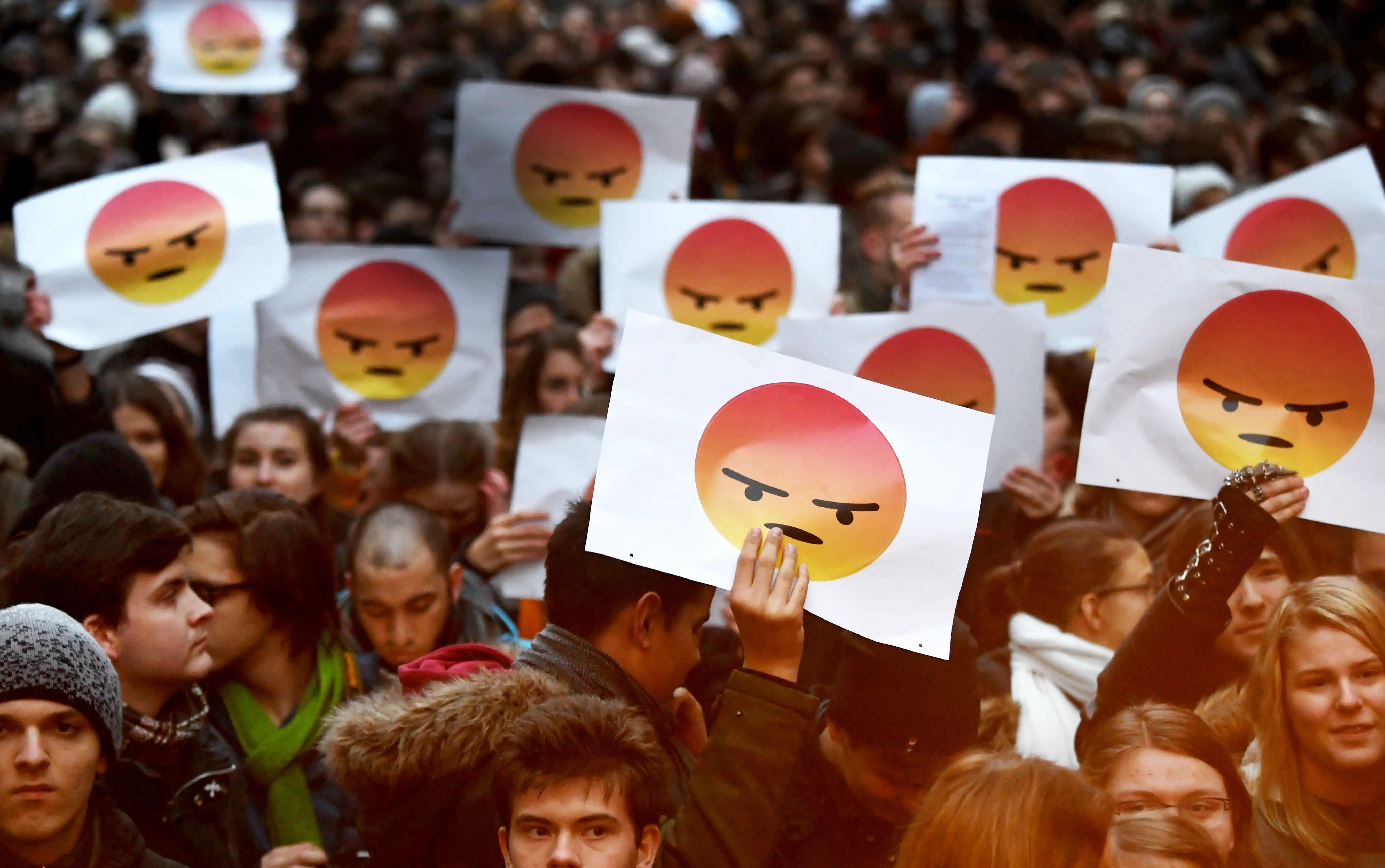 Protestors holding up angry emoji signs