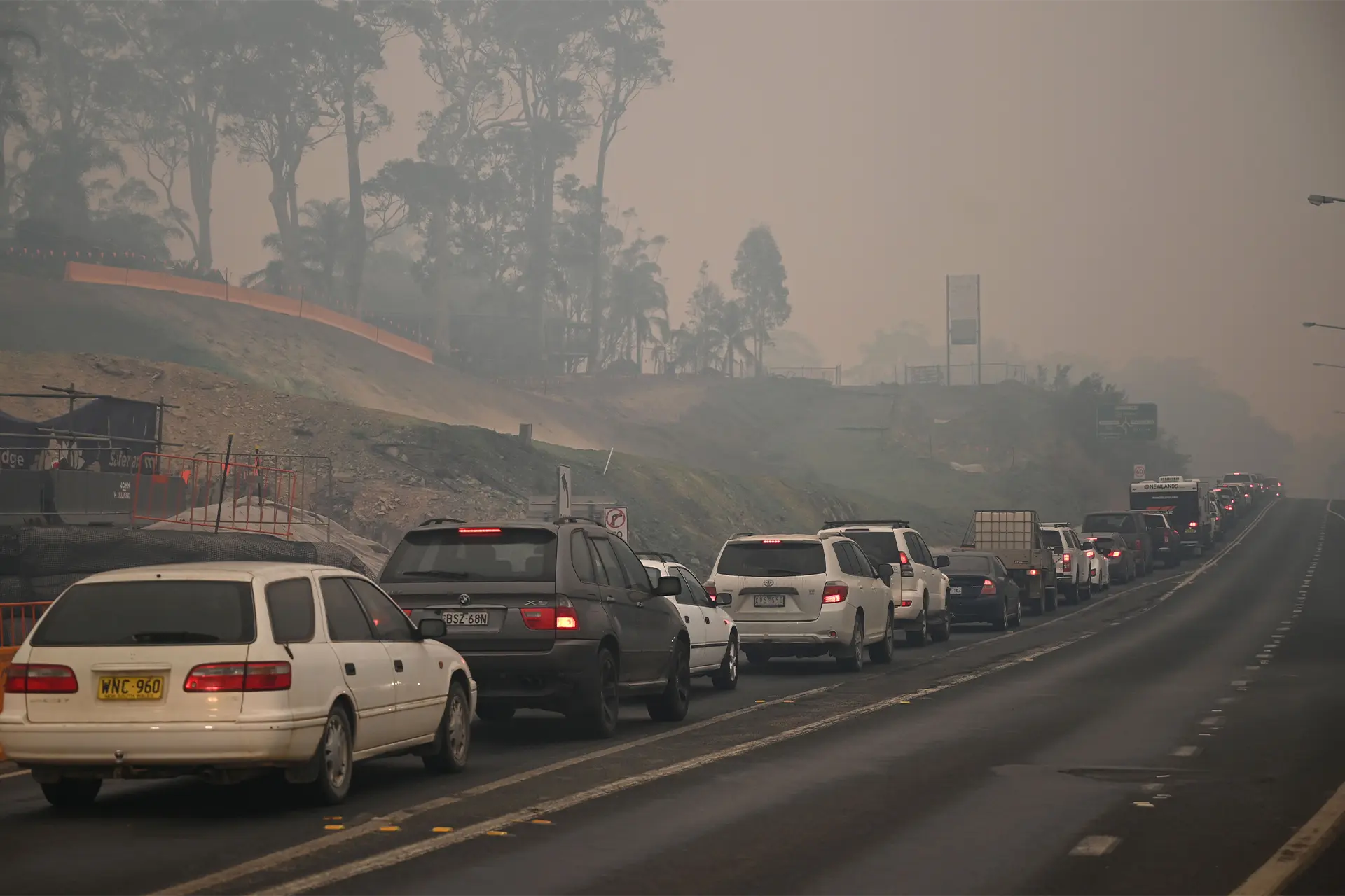 Car traffic driving through a rural area covered in smoke