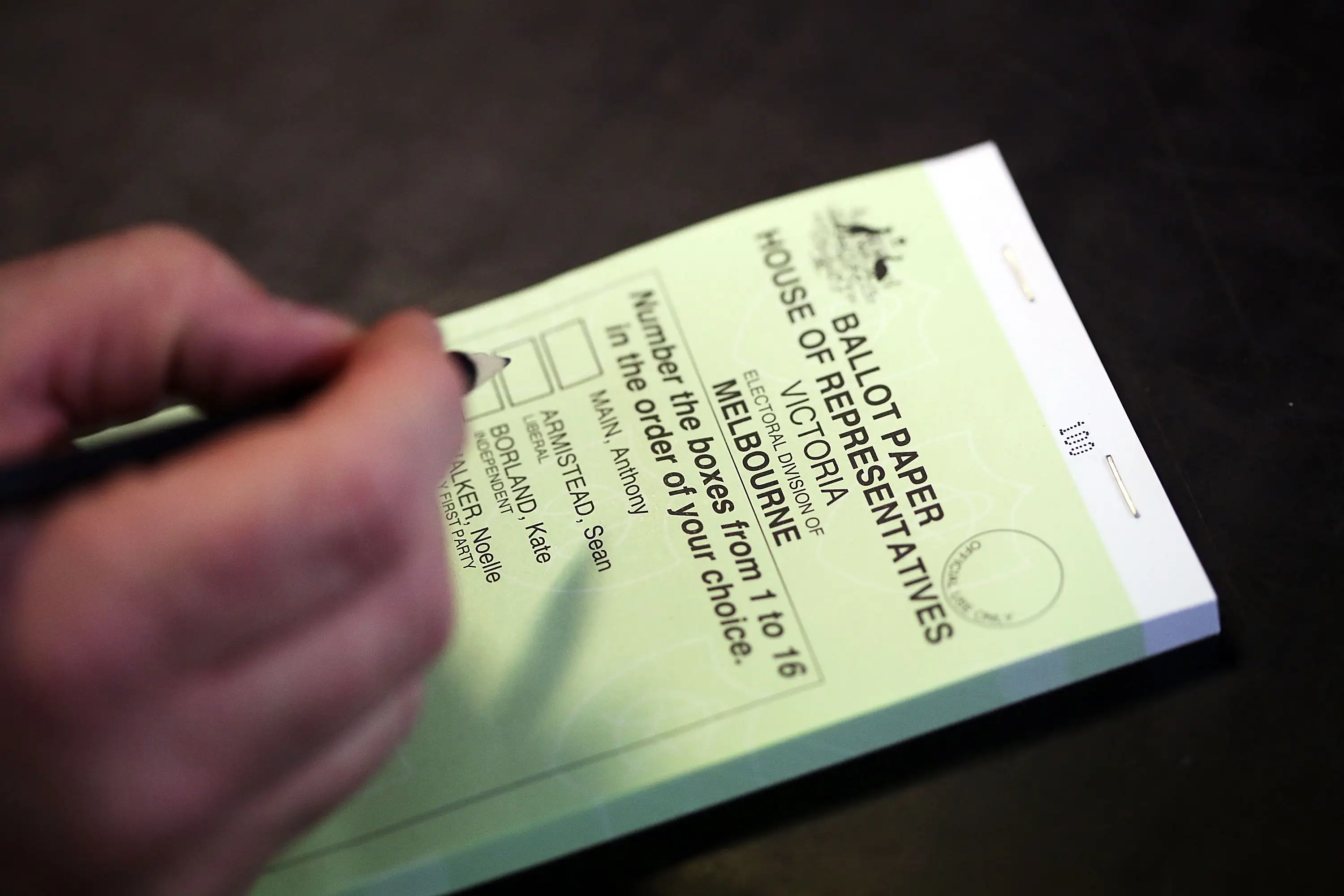 A close-up of a person filling out their ballot card