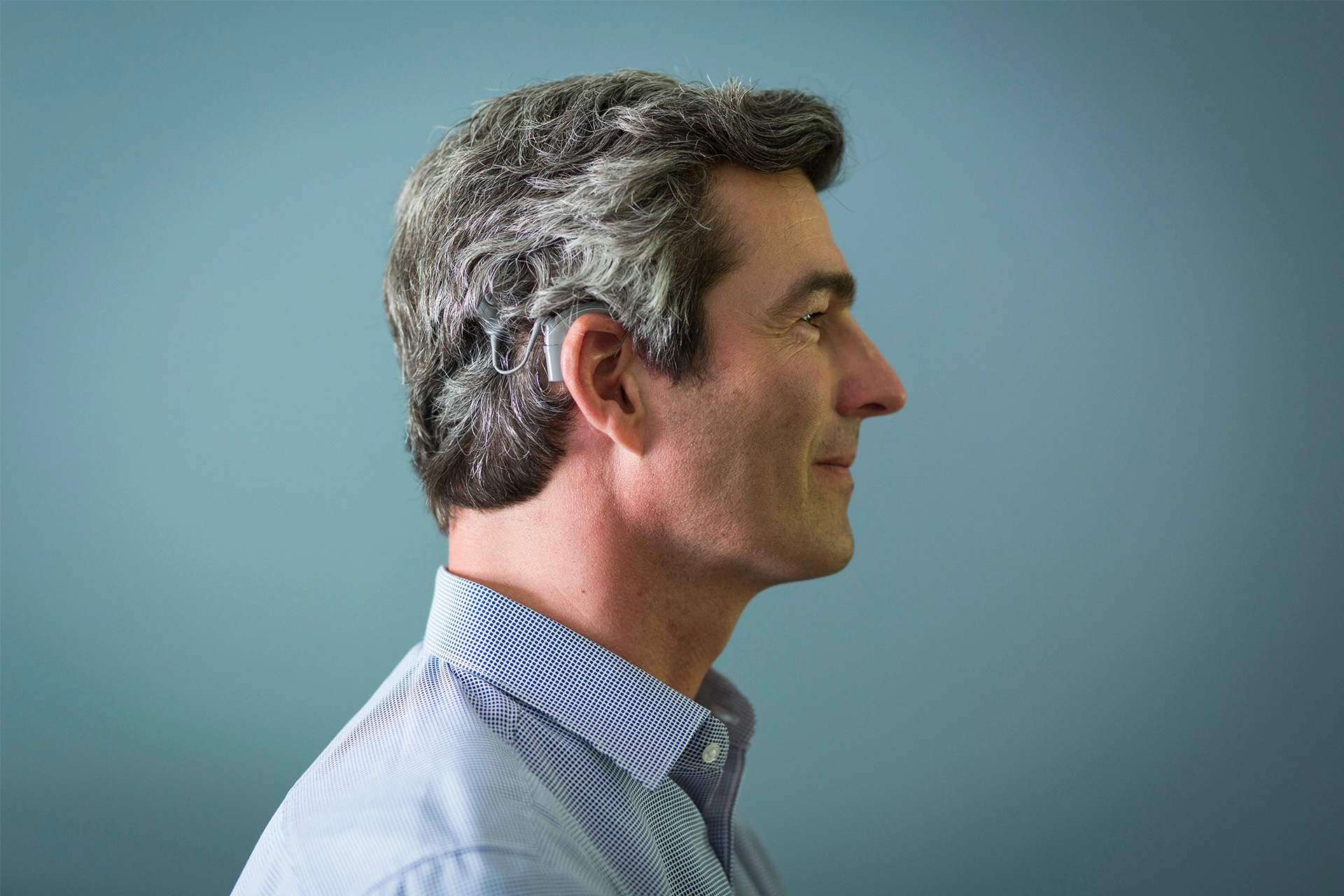 Side-on view of man's head and shoulders. Man is wearing a Cochlear implant