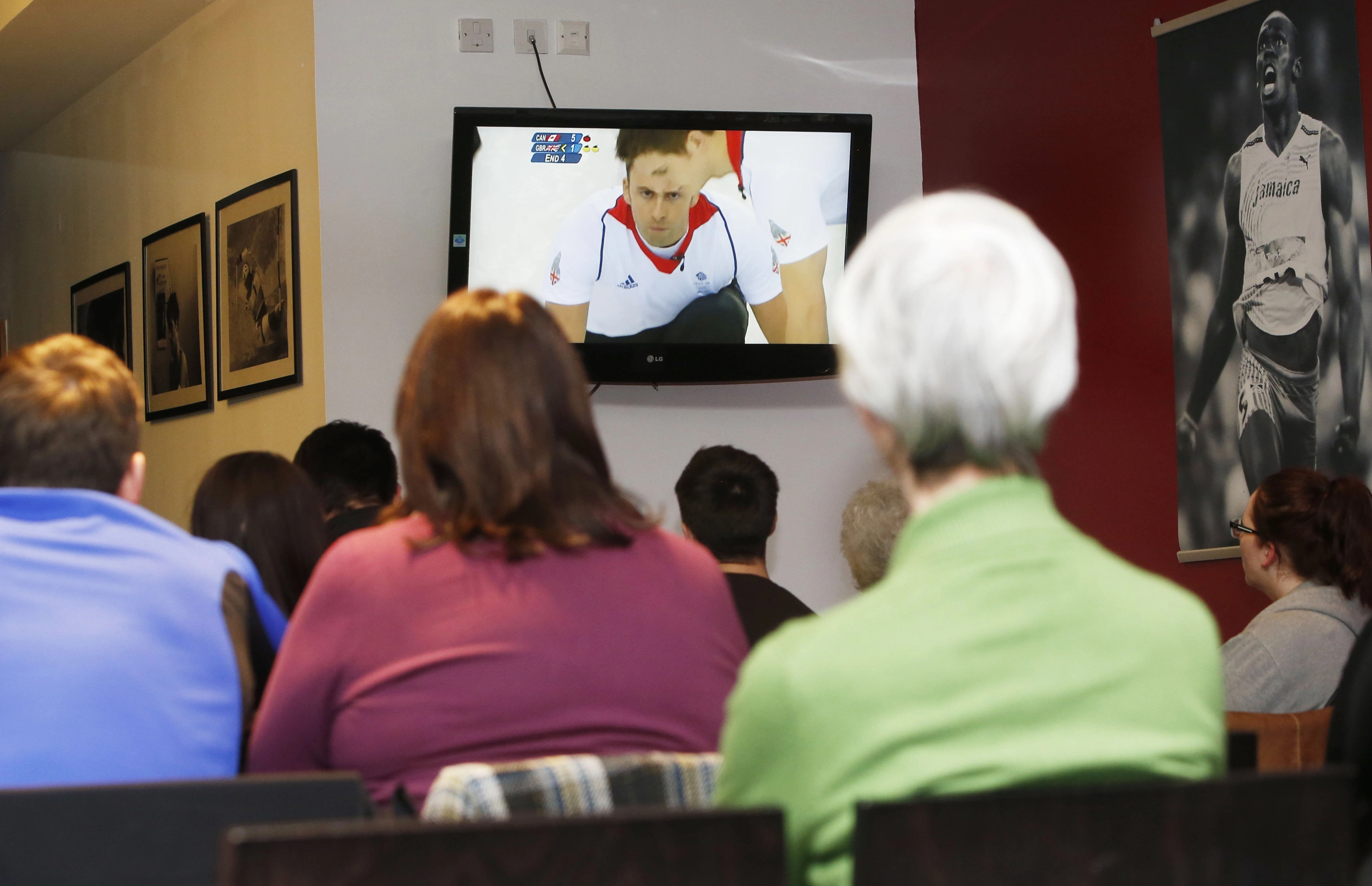 A shot from behind of people watching the Winter Olympics in a waiting room