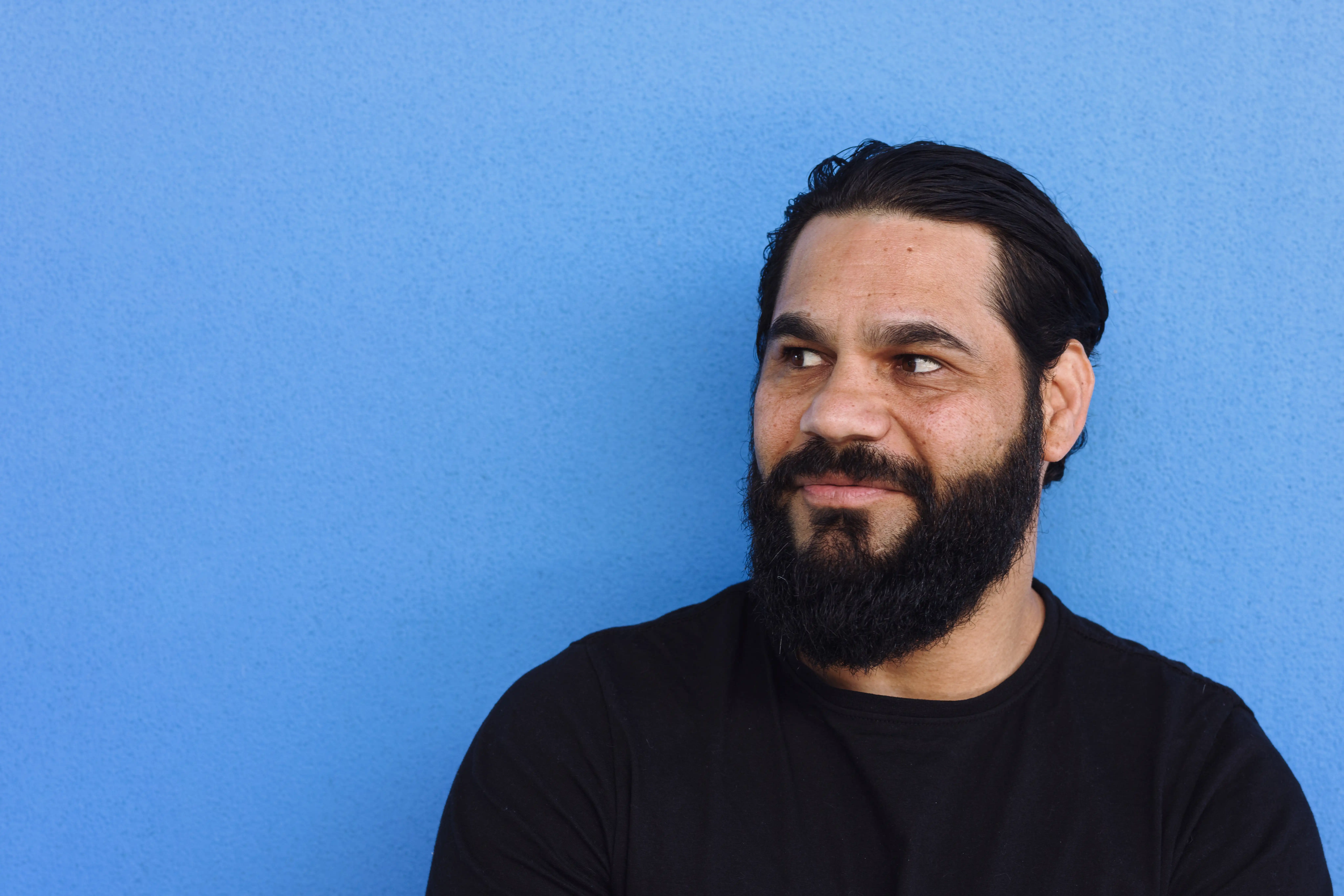 Portrait of Indigenous Australian man against a blue background looking off camera