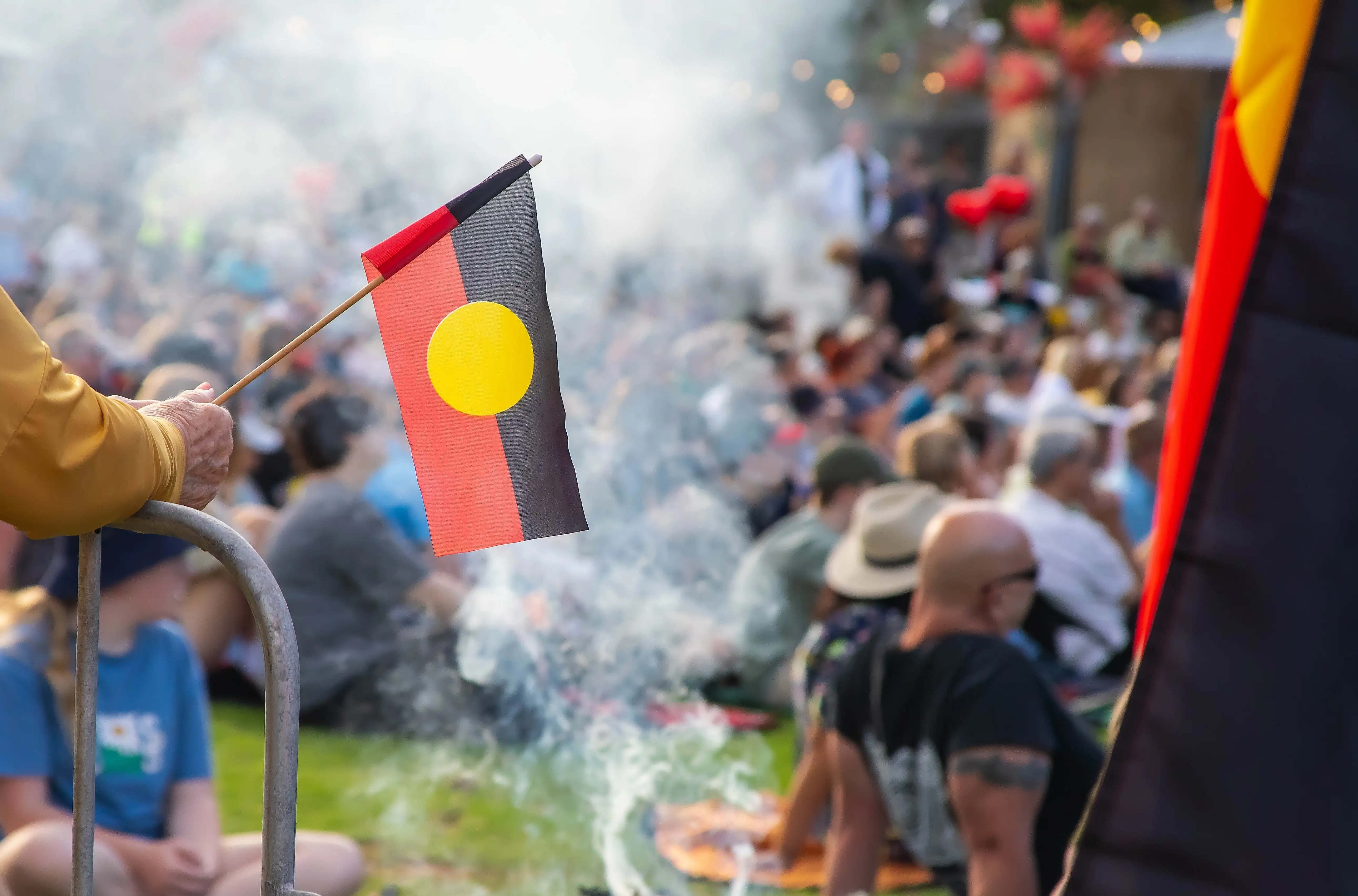 A person holds an Indigenous flag amid a crowd