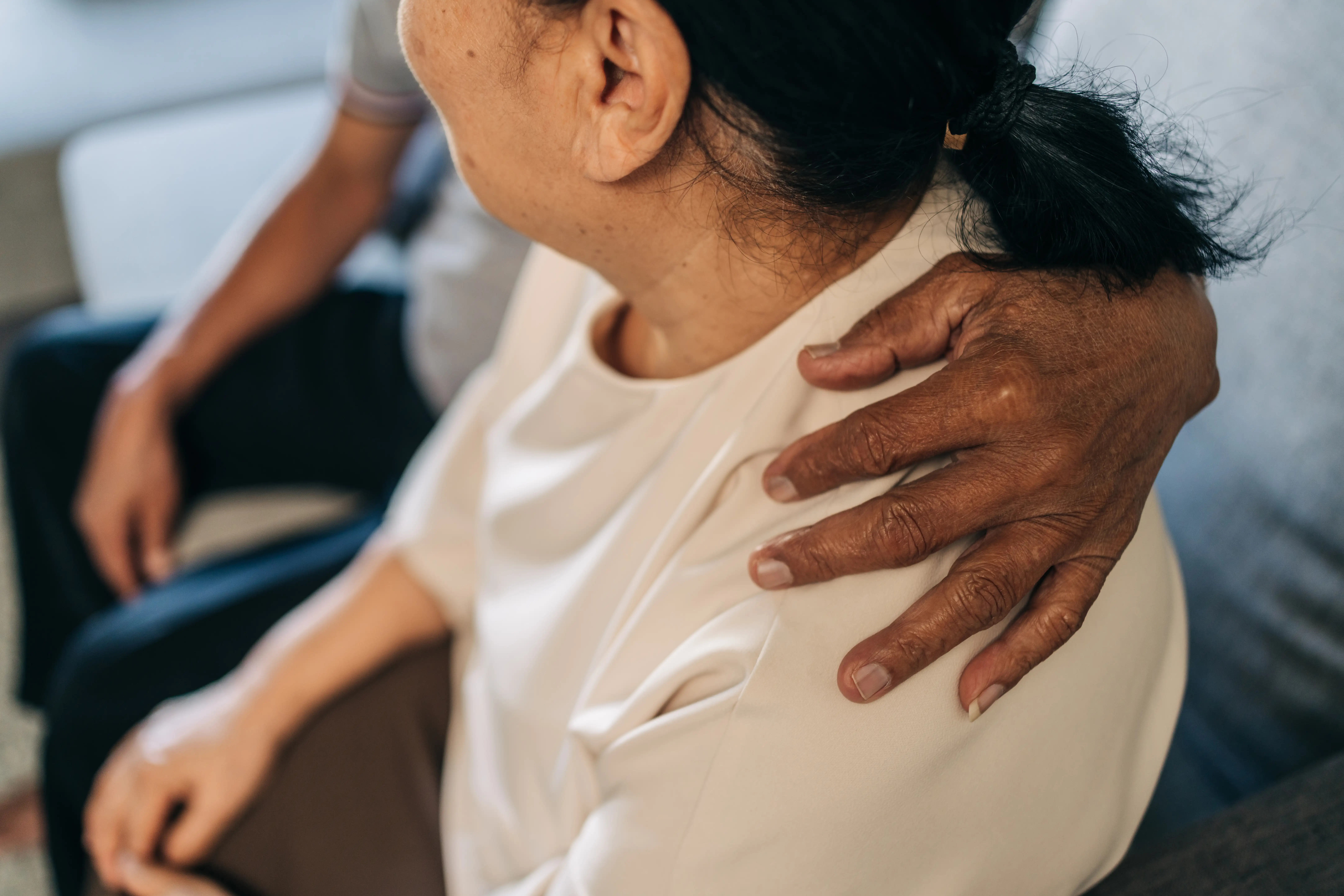 An older woman with someone's arm around her shoulder