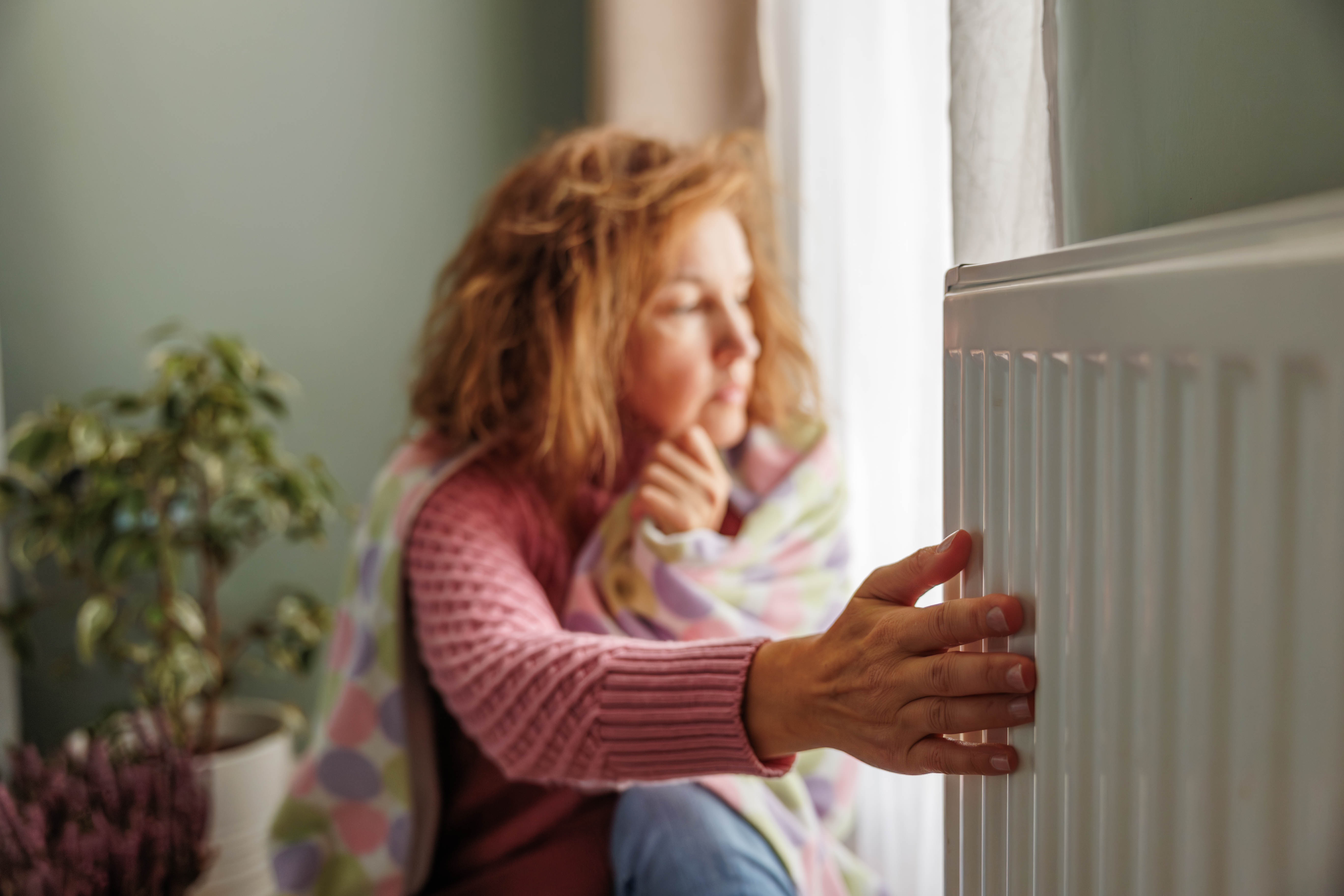 A woman reaches out to touch a heater inside