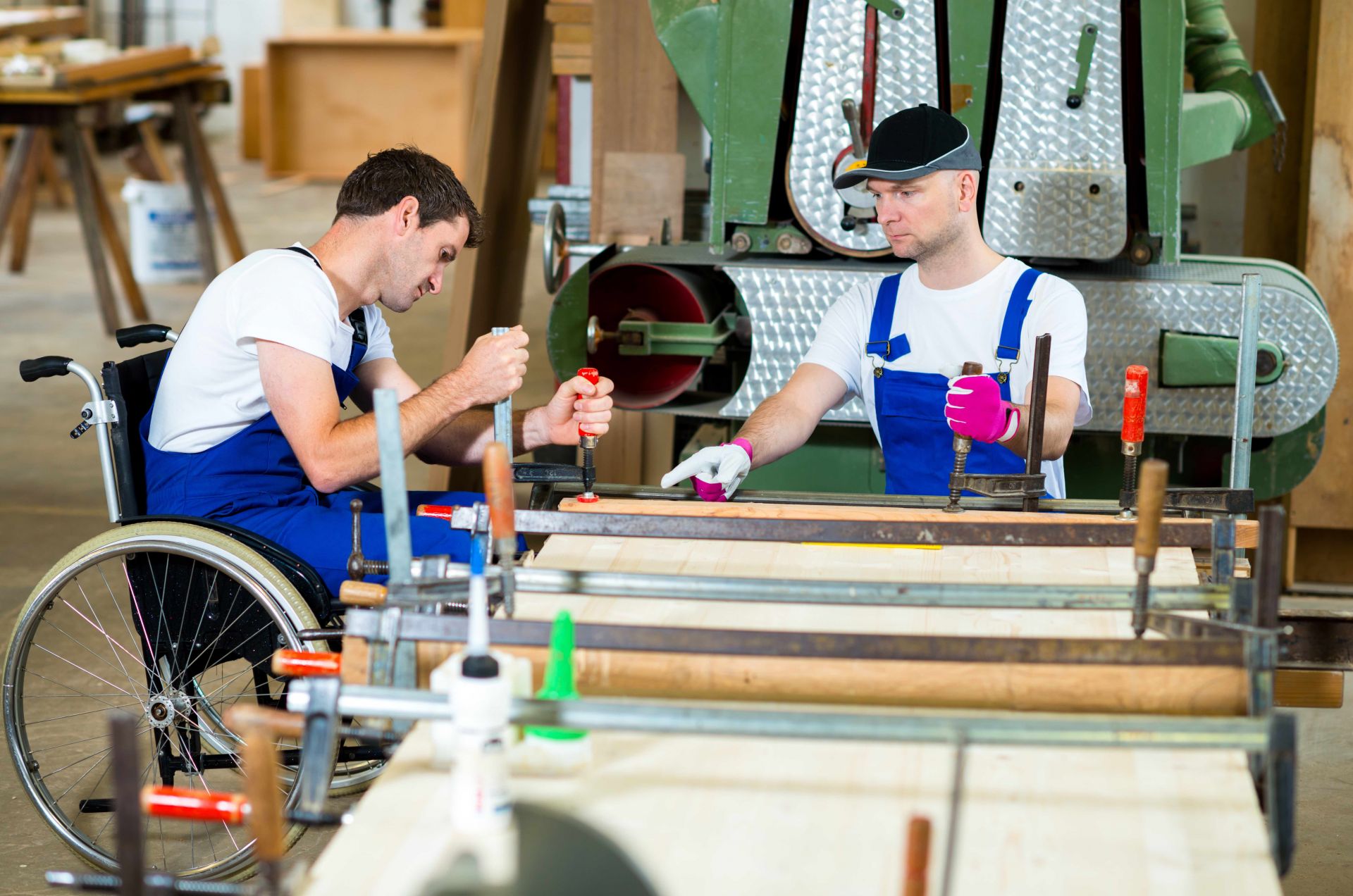 Two men working in a factory. One sits on a wheelchair