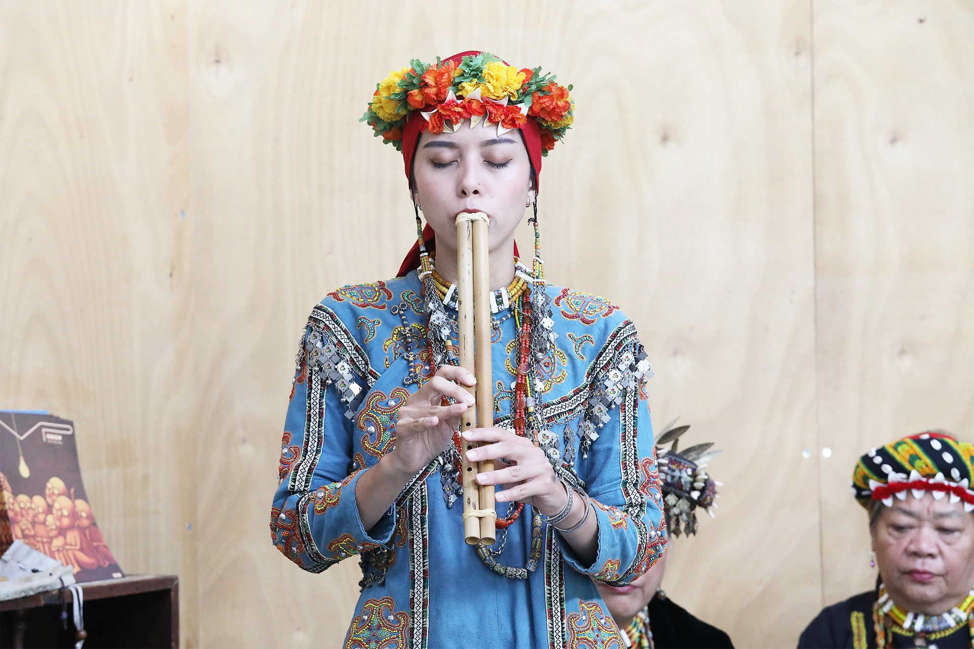 Woman in traditional Paiwan dress playing a nose flute