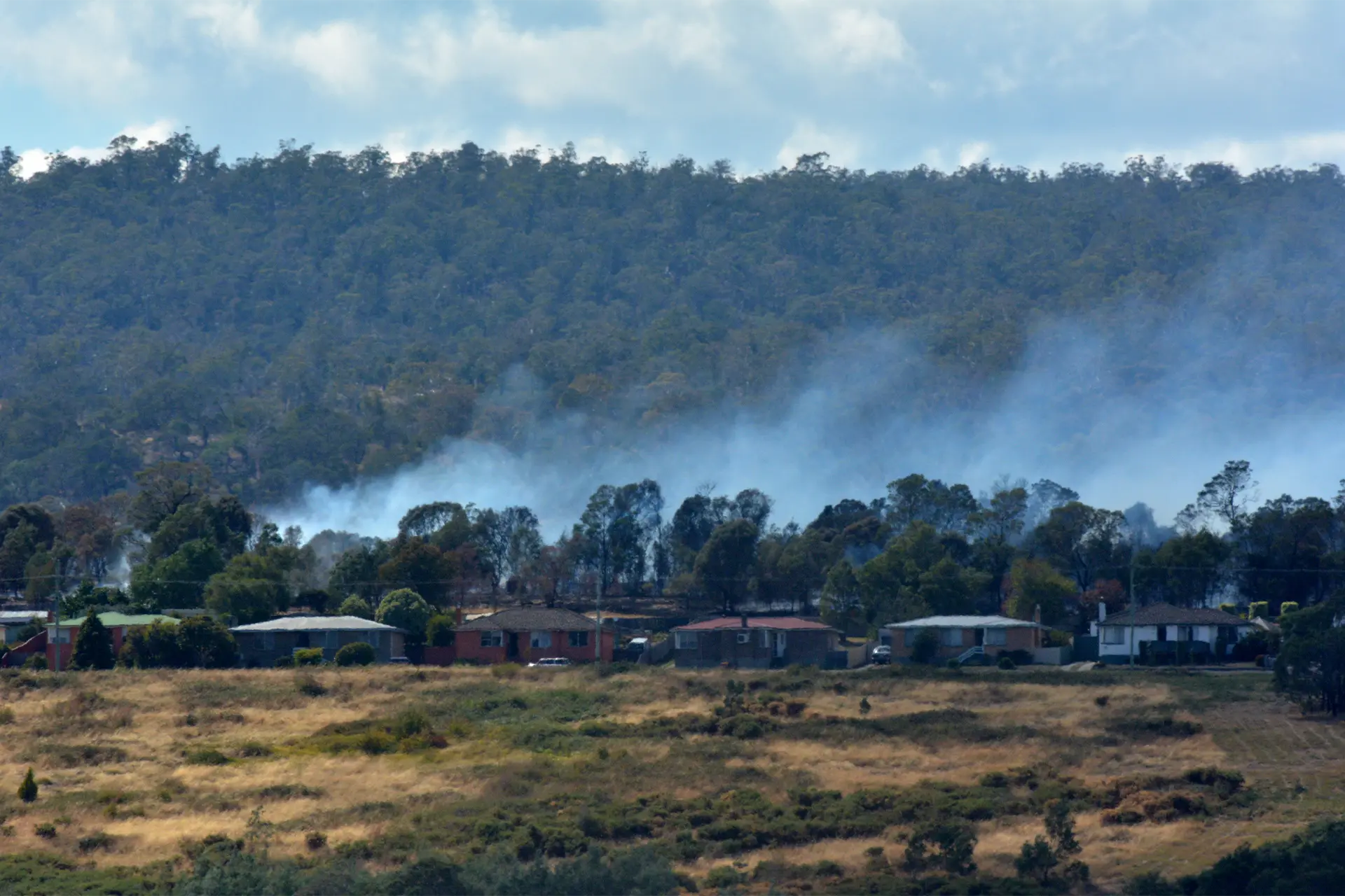 A row of houses with fire smoke behind them