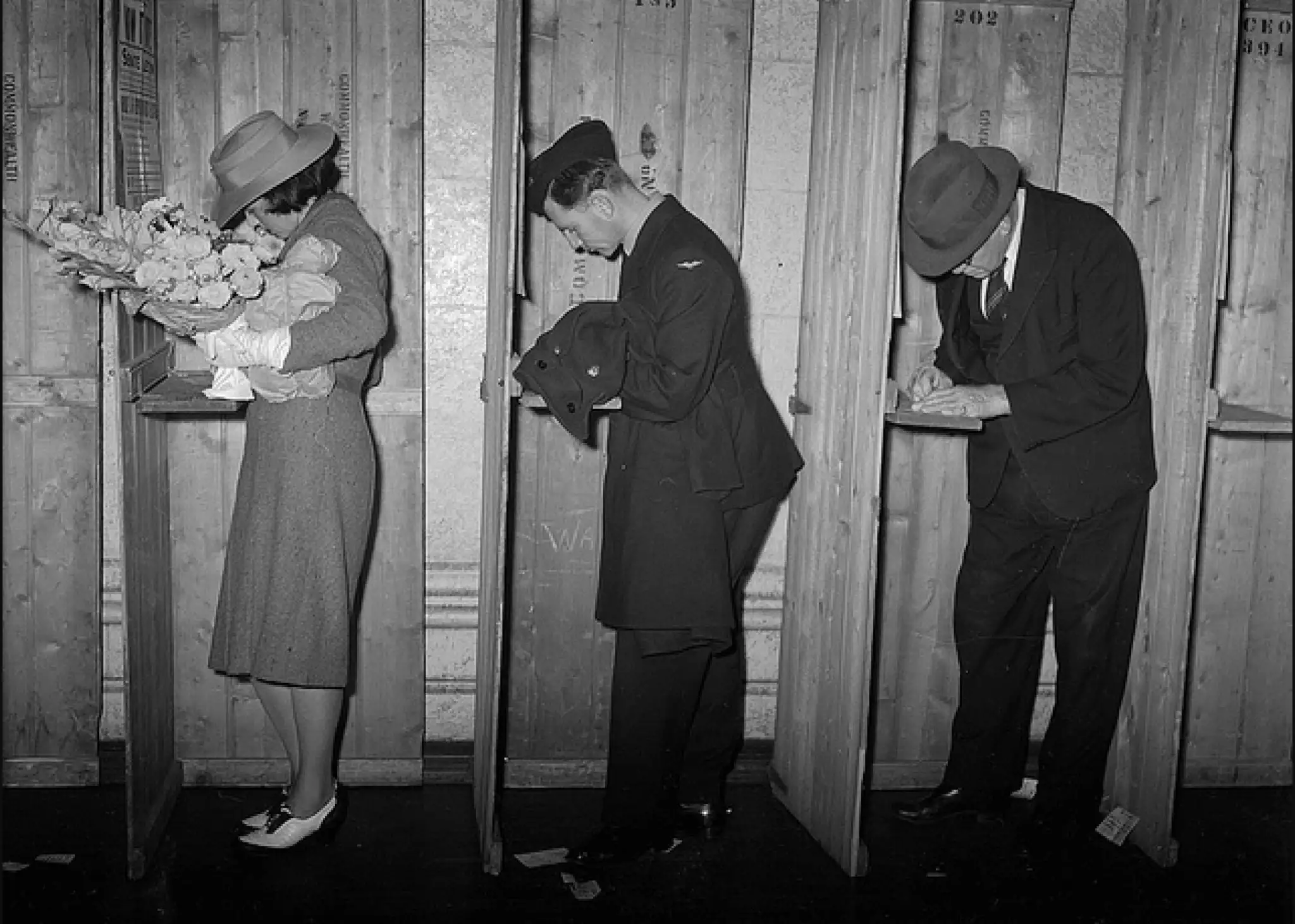 A black-and-white photo of three people voting