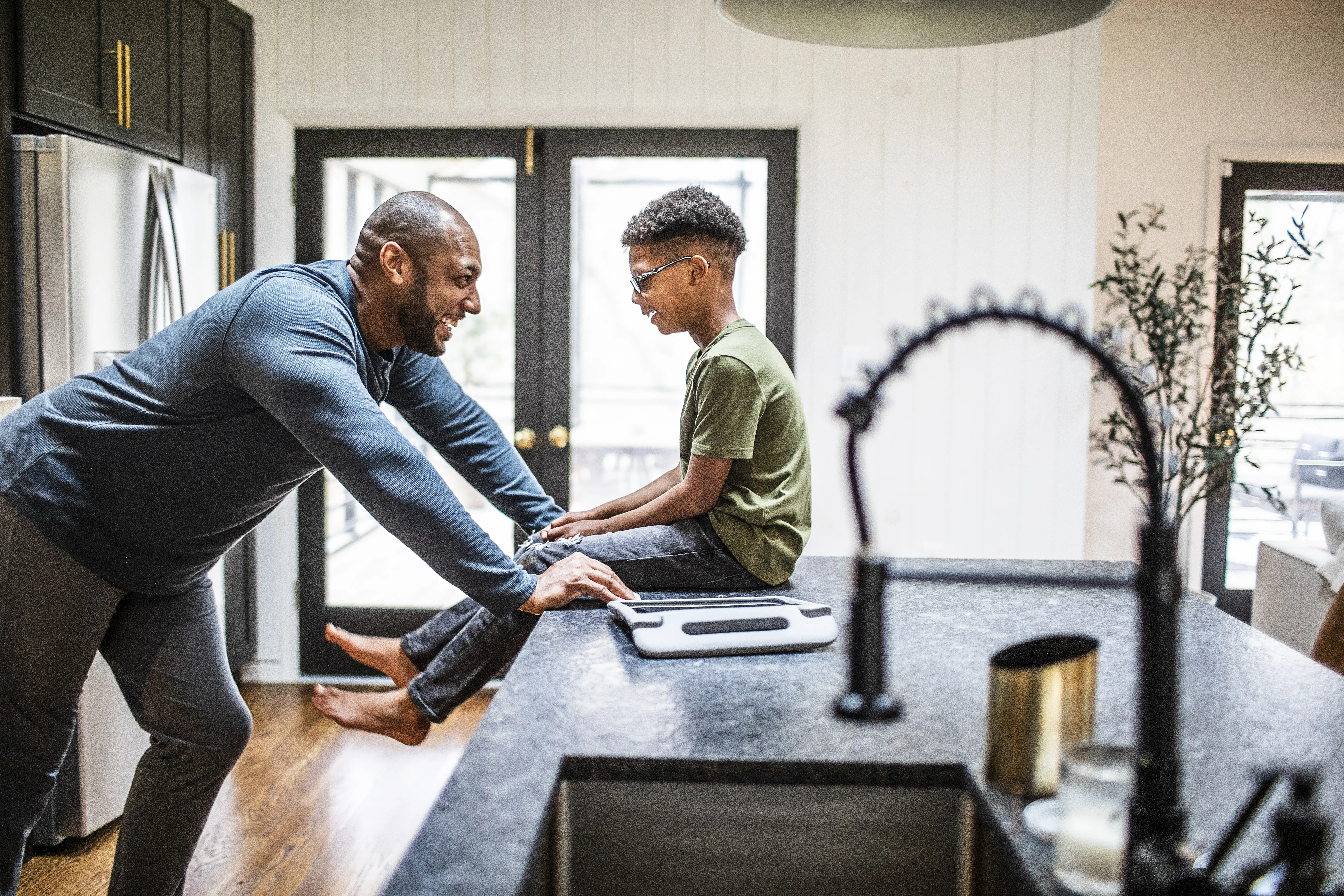 A father talking with his tween son in residential kitchen