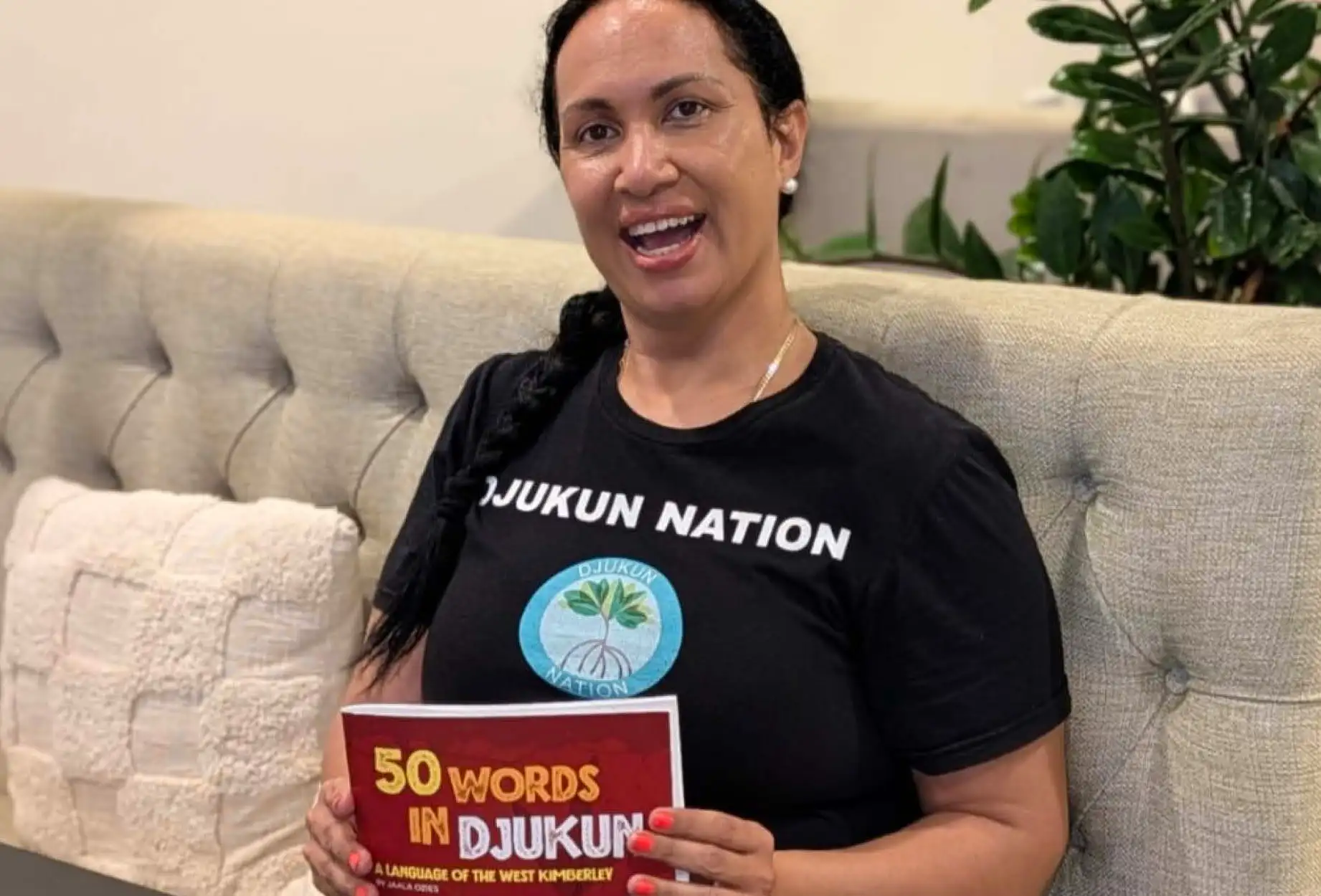 Jaala Ozies holding her book ’50 words in Djukun’ up.