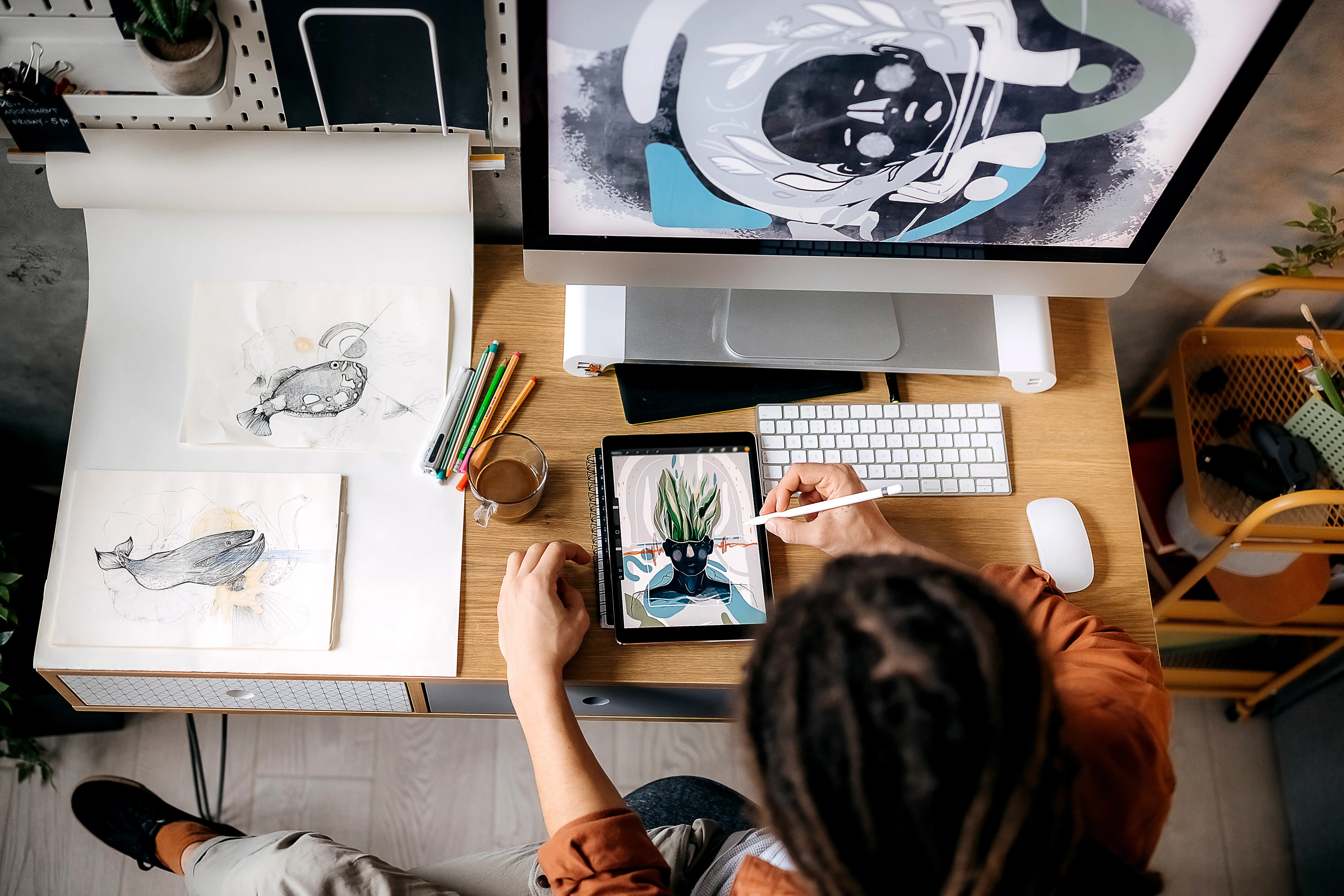 A graphic designer drawing artwork on a tablet at her desk