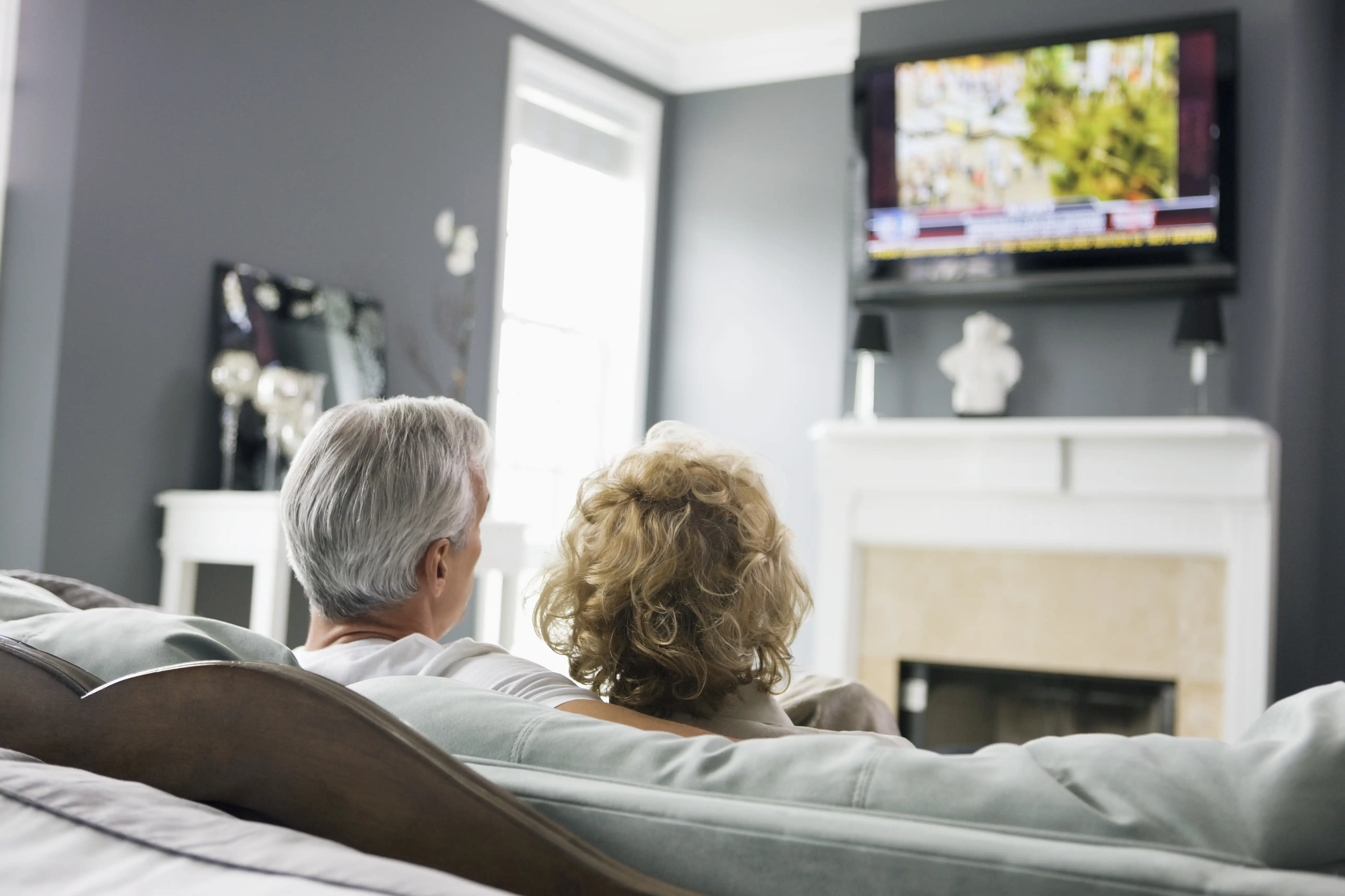An older couple watch the TV news together 