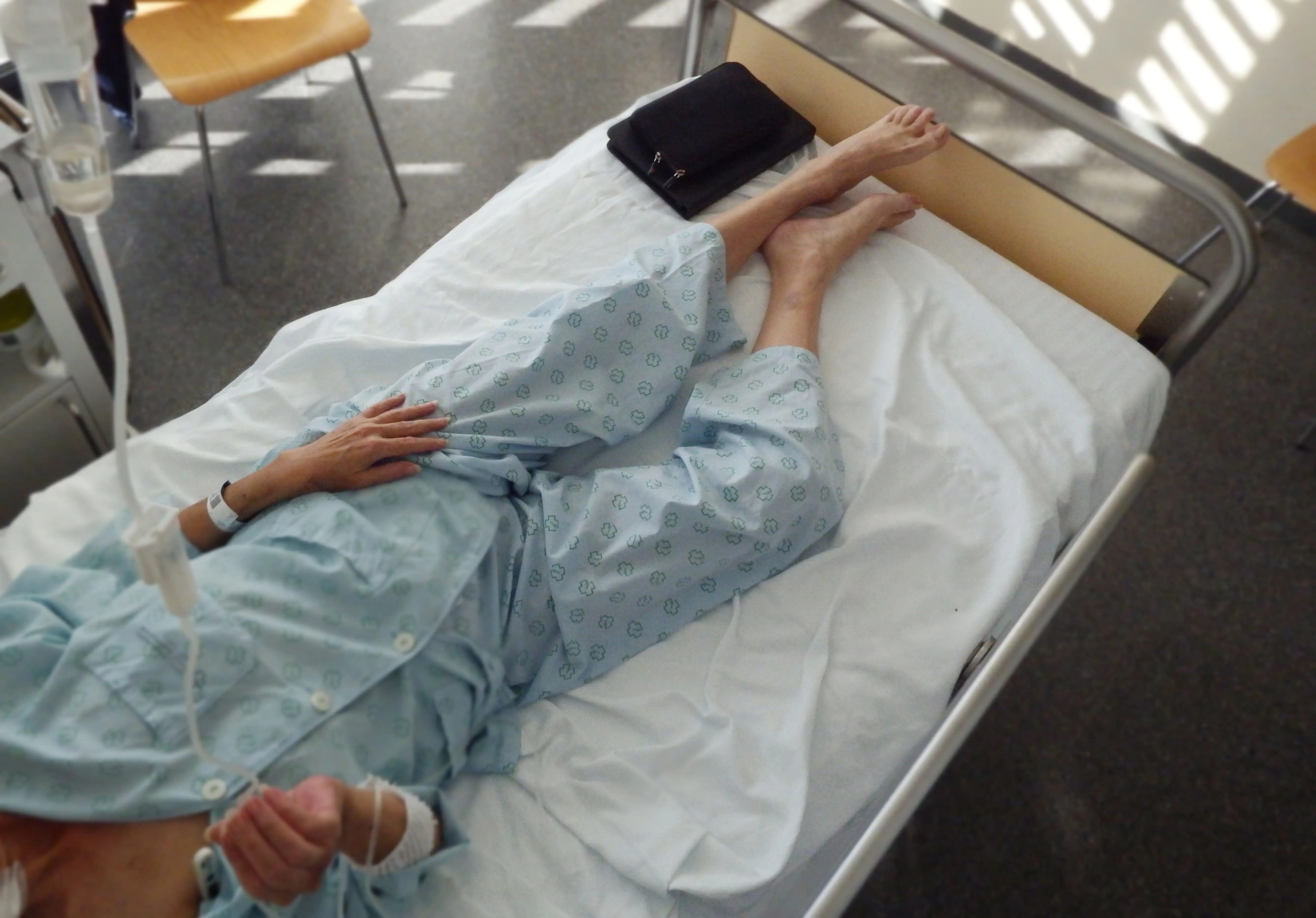 Elevated view of a sick woman lying on a hospital bed.
