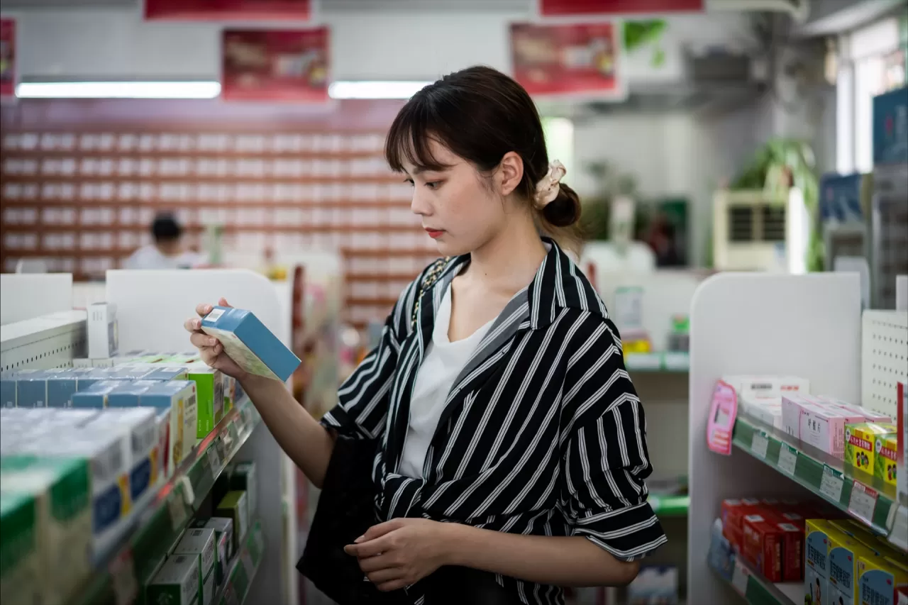 Woman looking at a product taken from a shelf at a chemist