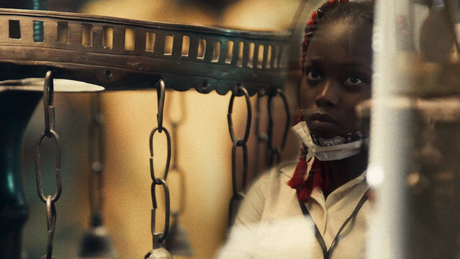 A movie still of a woman standing next to some hanging chains