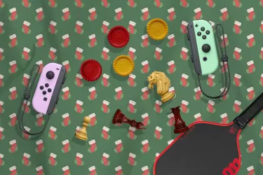 A banner image of Christmas wrapping paper and a selection of different game pieces, a pickleball racket and a pair of game controllers seemingly tossed in the air.