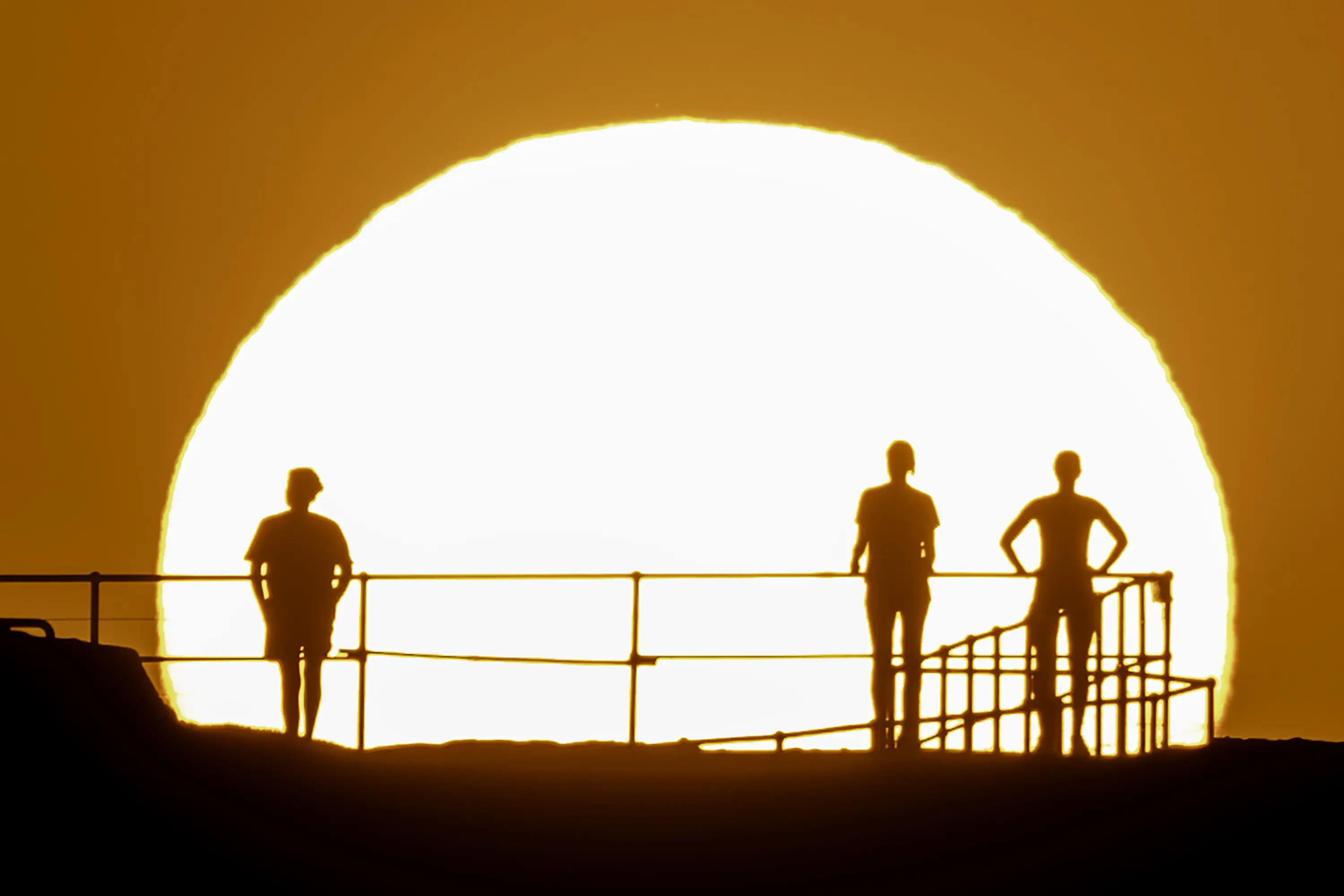  People watch as a red sun rises over Ben Buckler Point in Bond