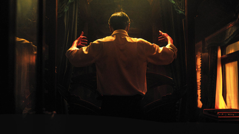 Man who appears to be conducting an unseen orchestra in the dark