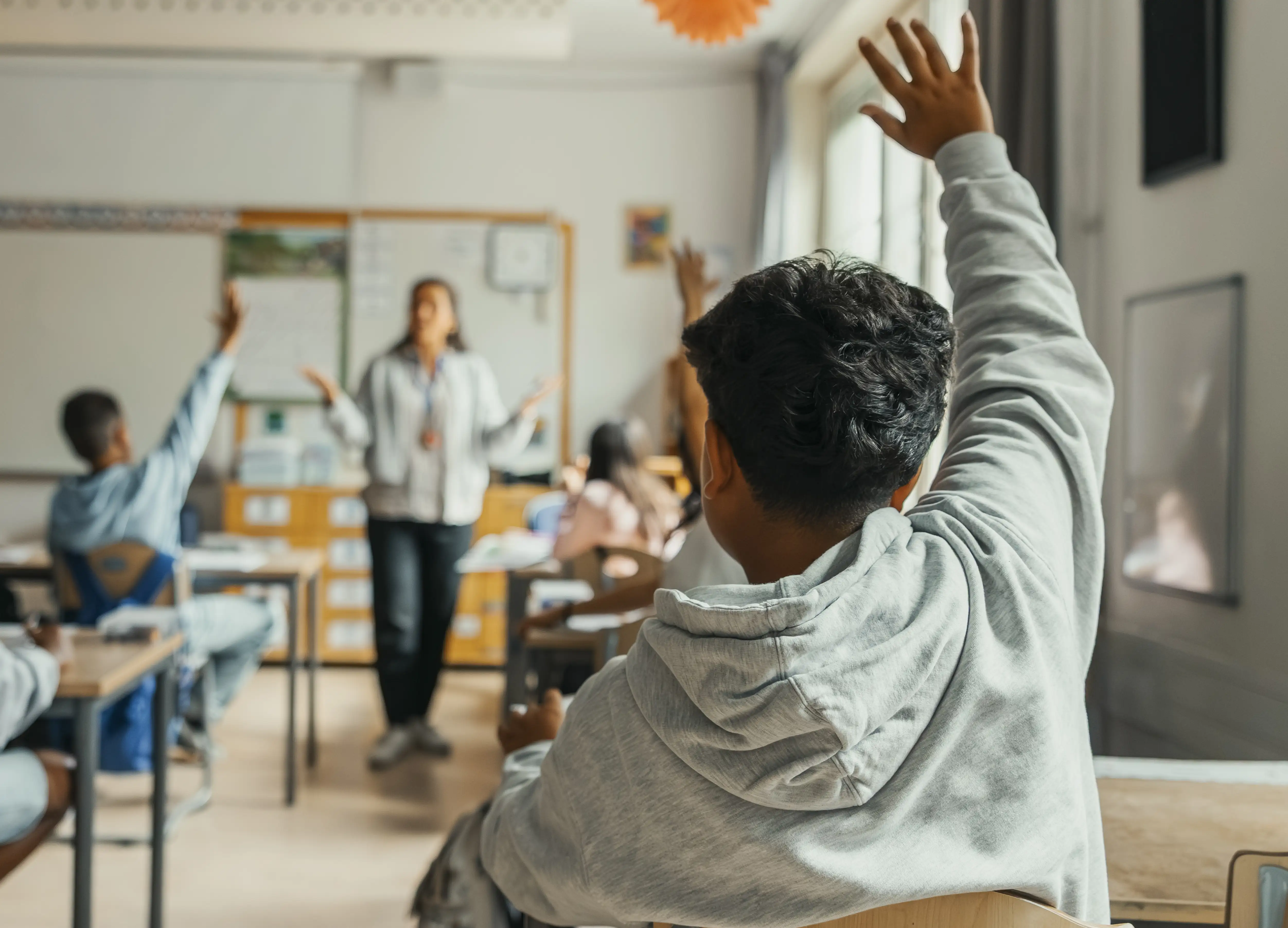 Children in a classroom raising their hands