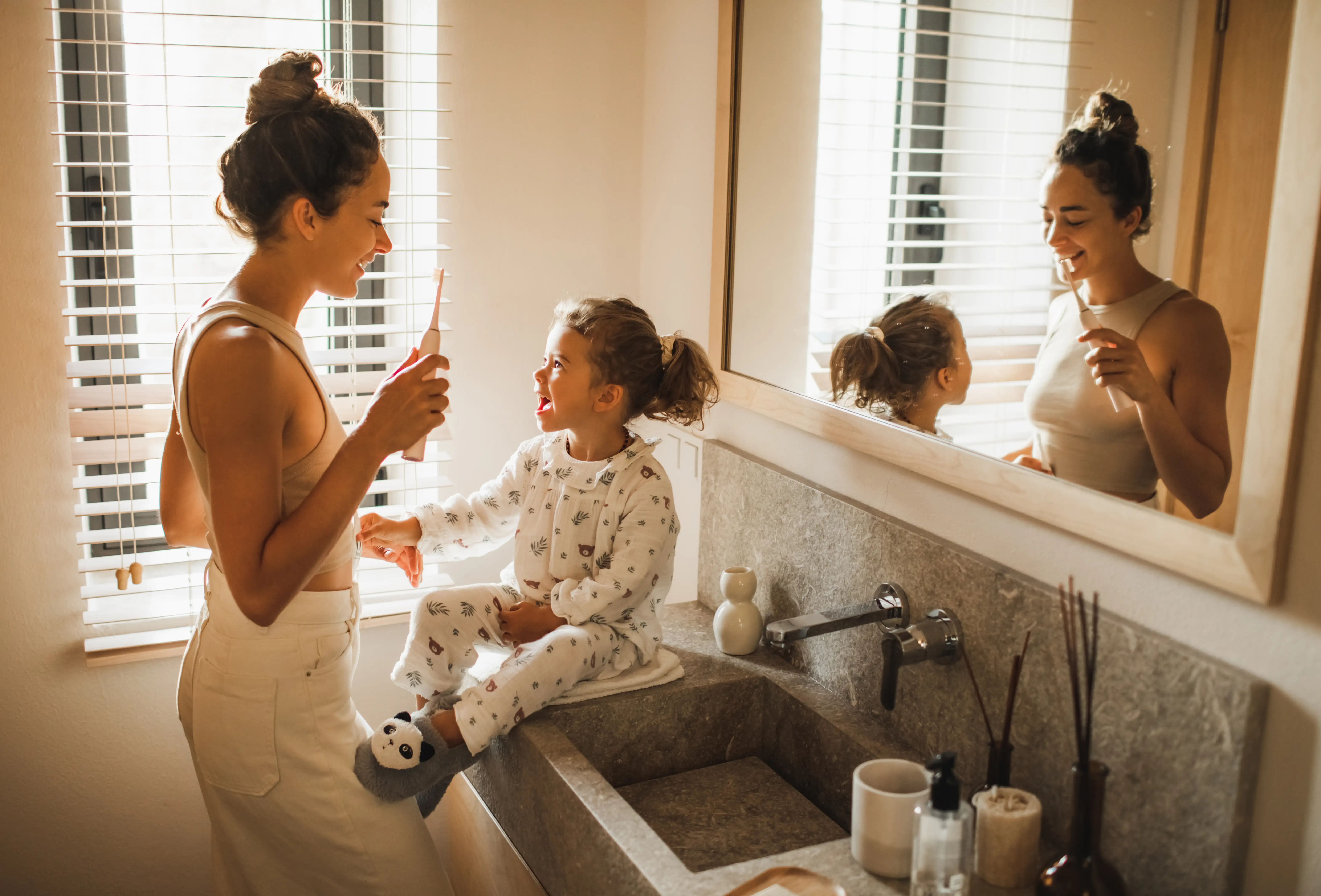 Mother and daughter cleaning their teeth in the bathroom