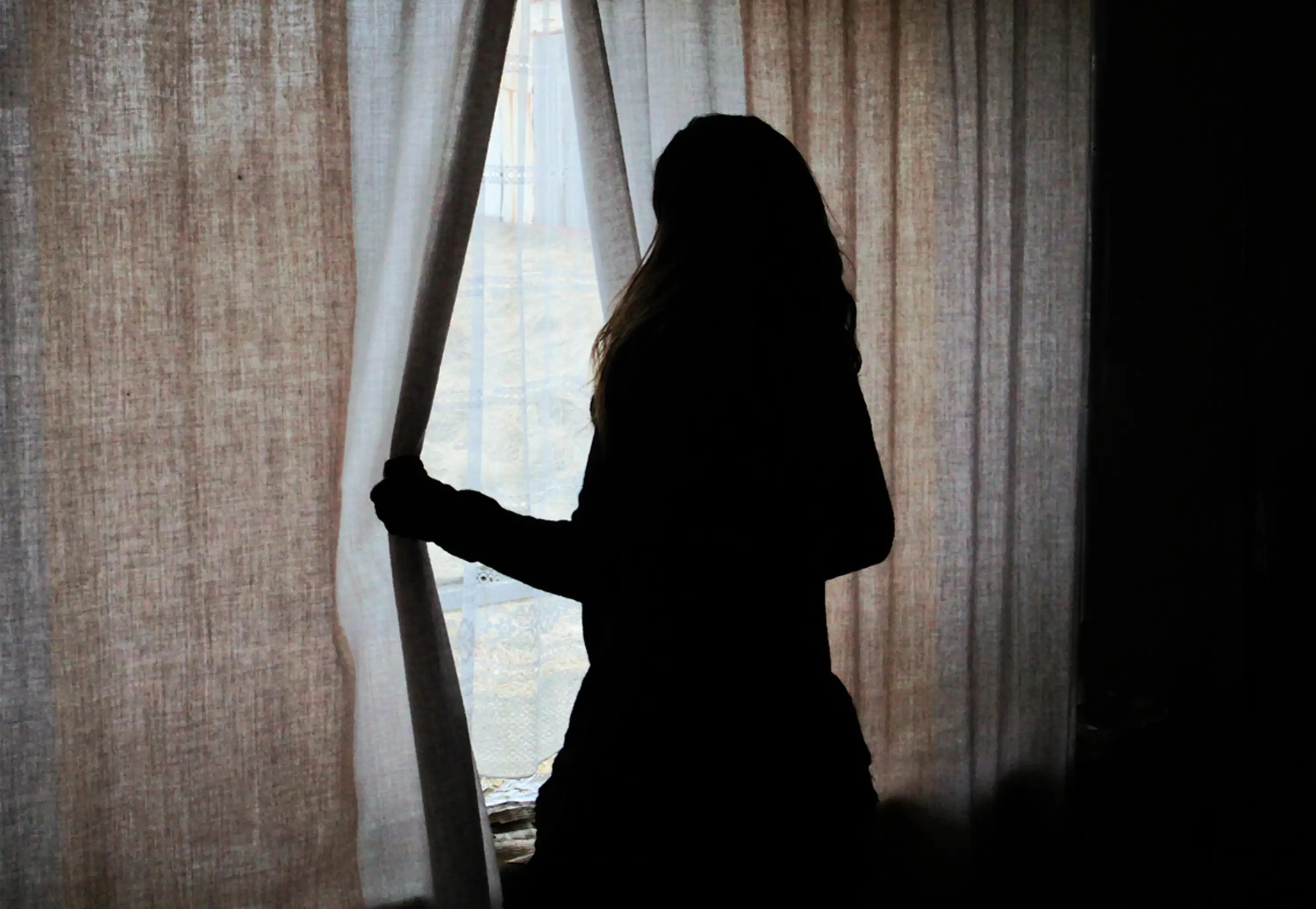 A silhouette of a woman at a window