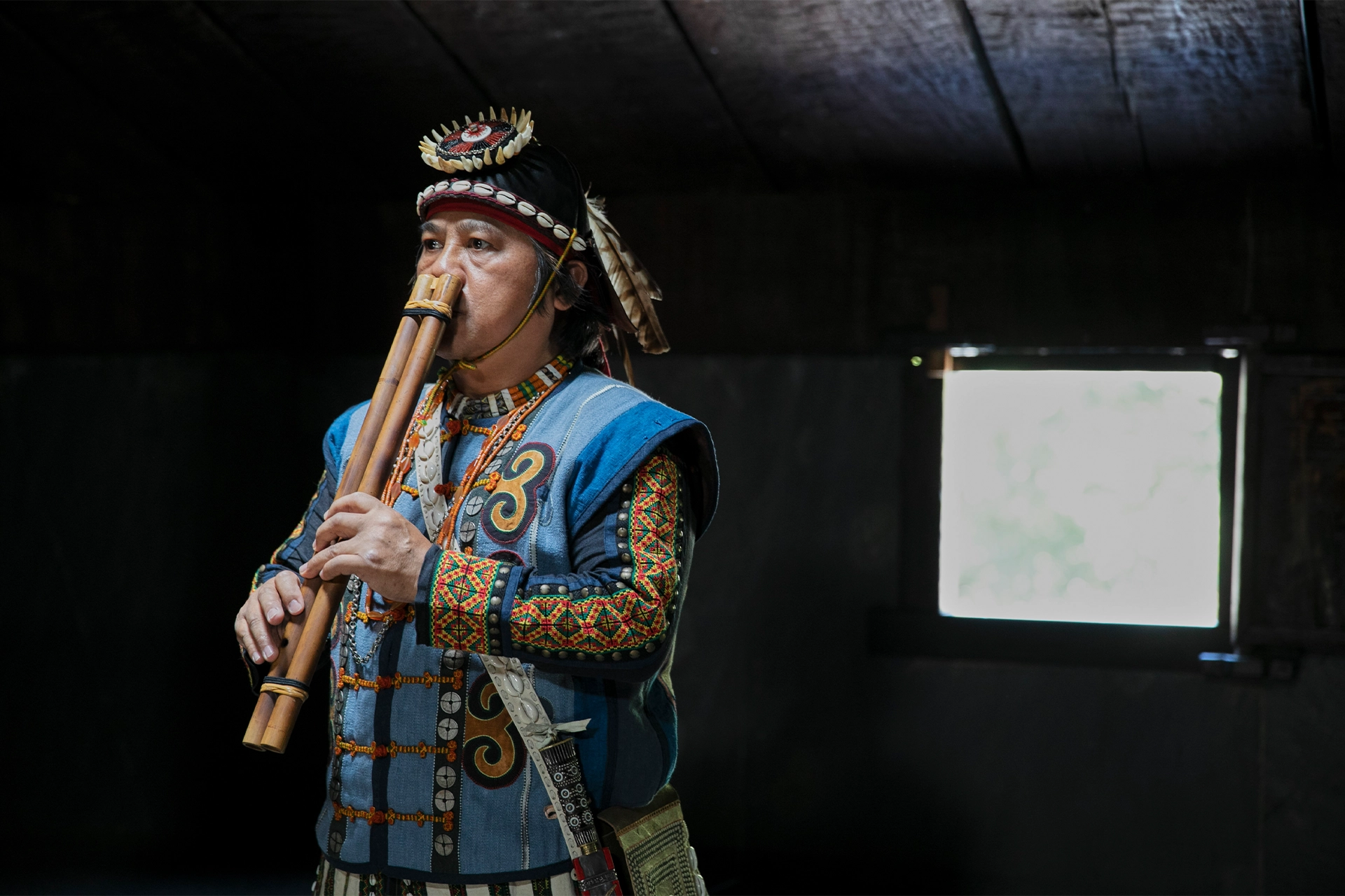 Man in traditional Paiwan clothes playing a nose flute