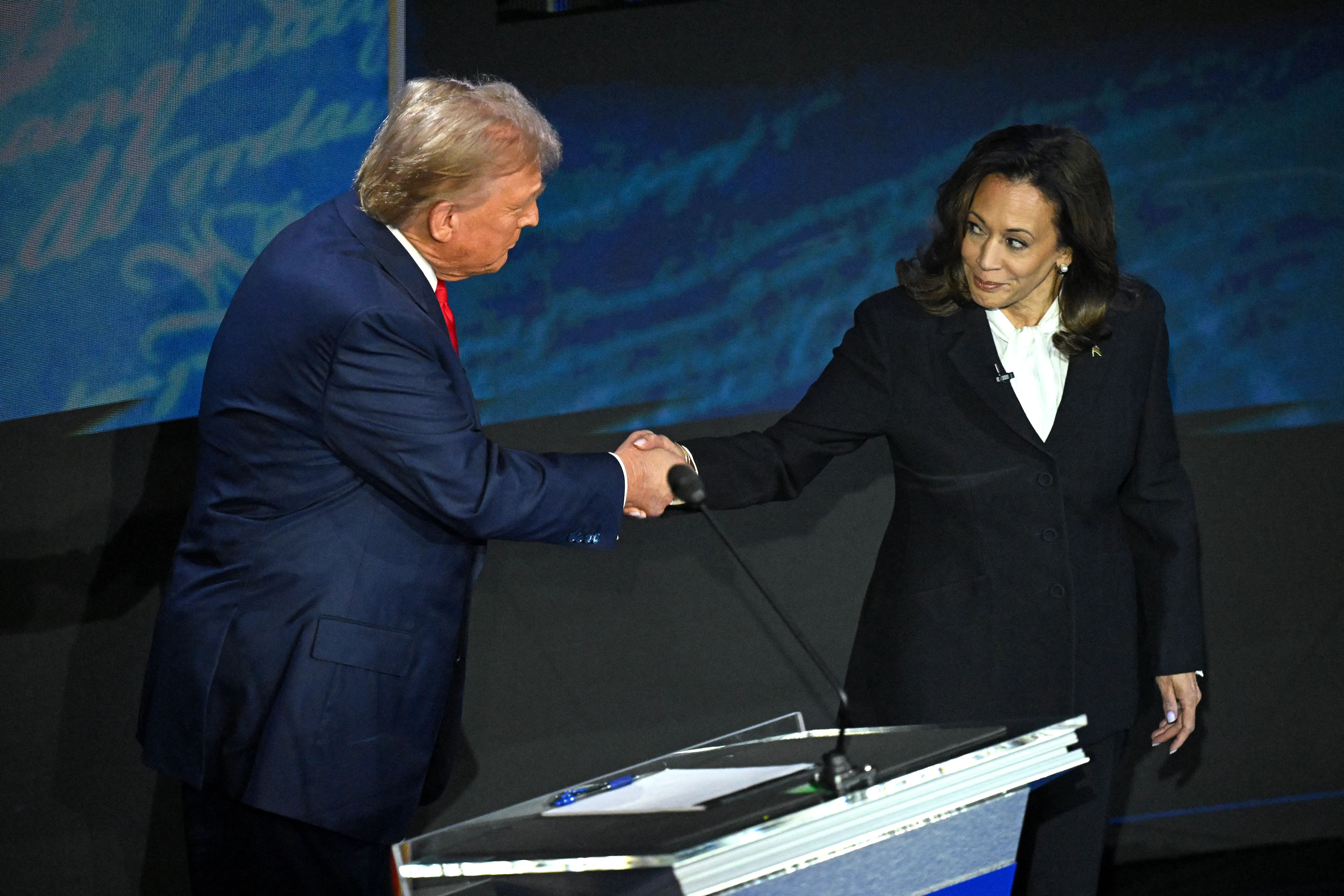 US Vice President and Democratic presidential candidate Kamala Harris (R) shakes hands with former US President and Republican presidential candidate Donald Trump