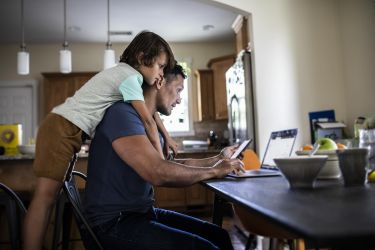 Dad with kid over shoulder on laptop