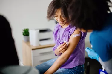 Teen girl getting her HPV vaccine at doctor's office while accompanied by her mother