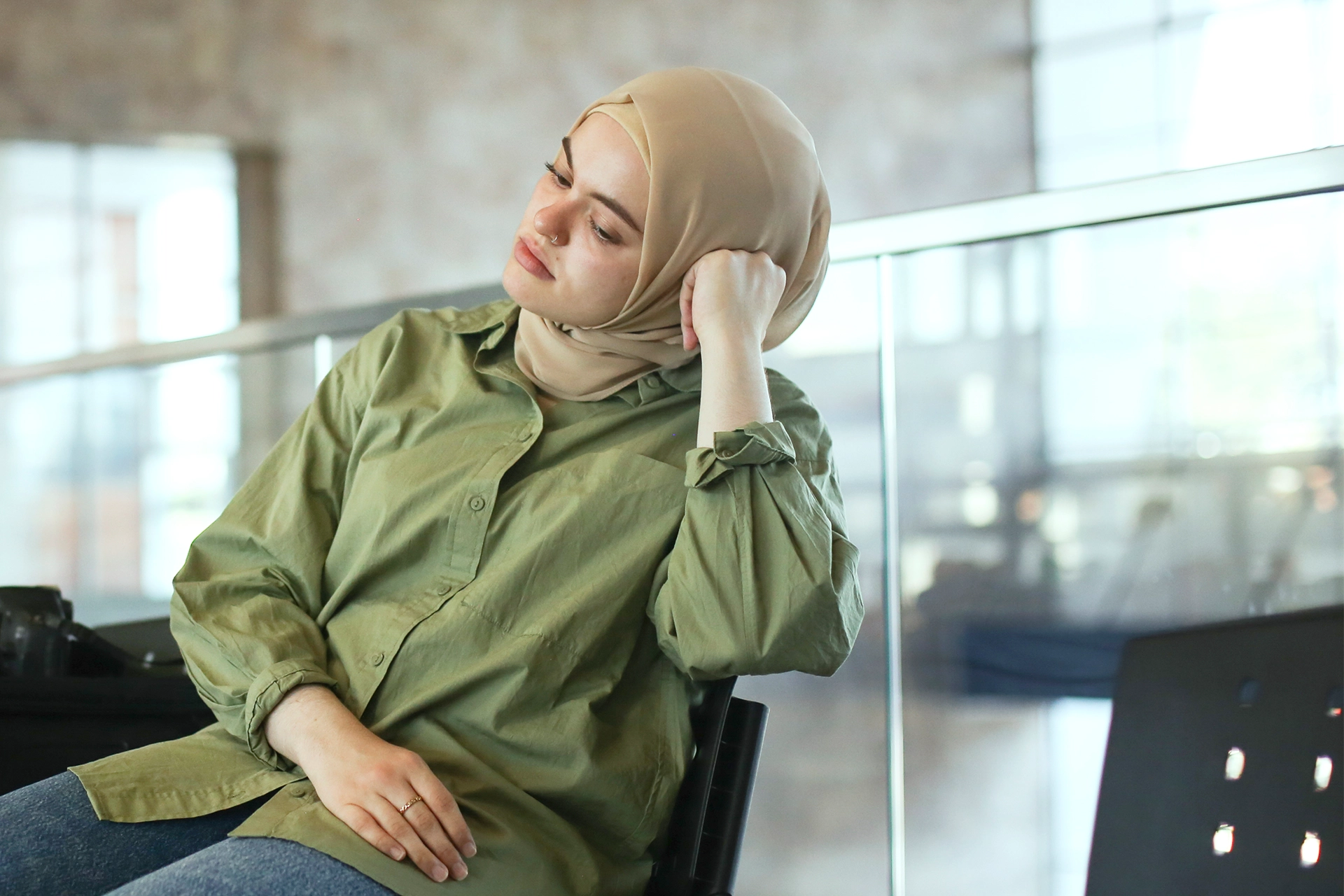 Young muslim woman sitting in a waiting room, resting her head on her hand