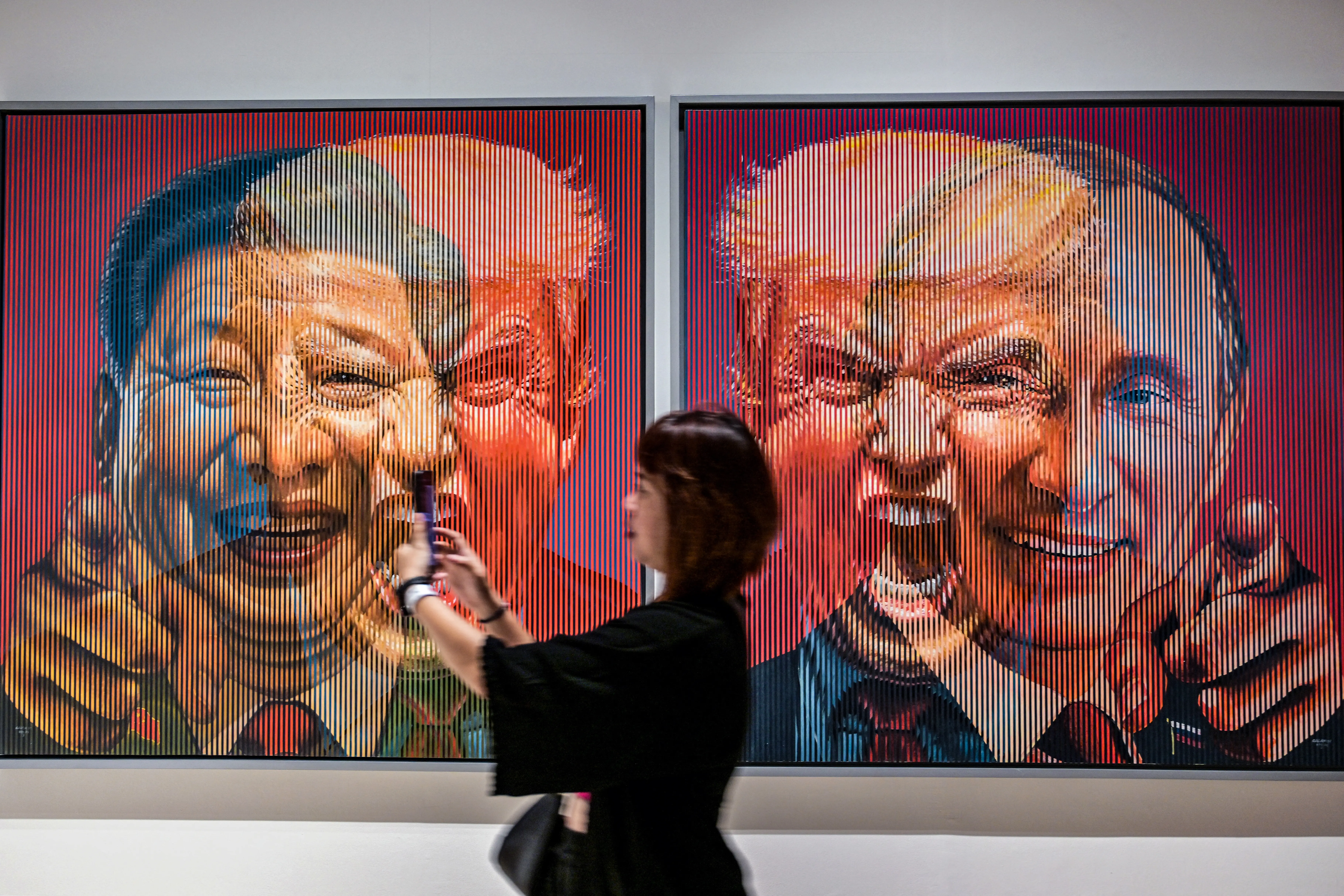 A visitor stands near an art installation by Galam Zulkifli portraying country Presidents (L-R) China's Xi Jinping, US Donald Trump and Russia's Vladimir Putin