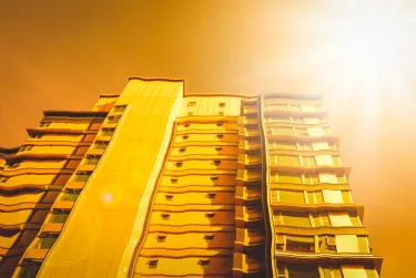 An apartment building distorted by heat with the summer sun above.