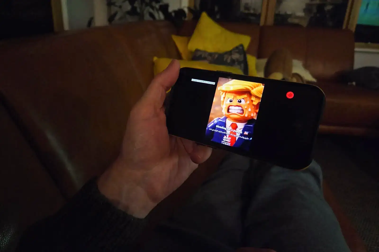 A person watching an Iranian AI-generated Lego video on a smartphone.