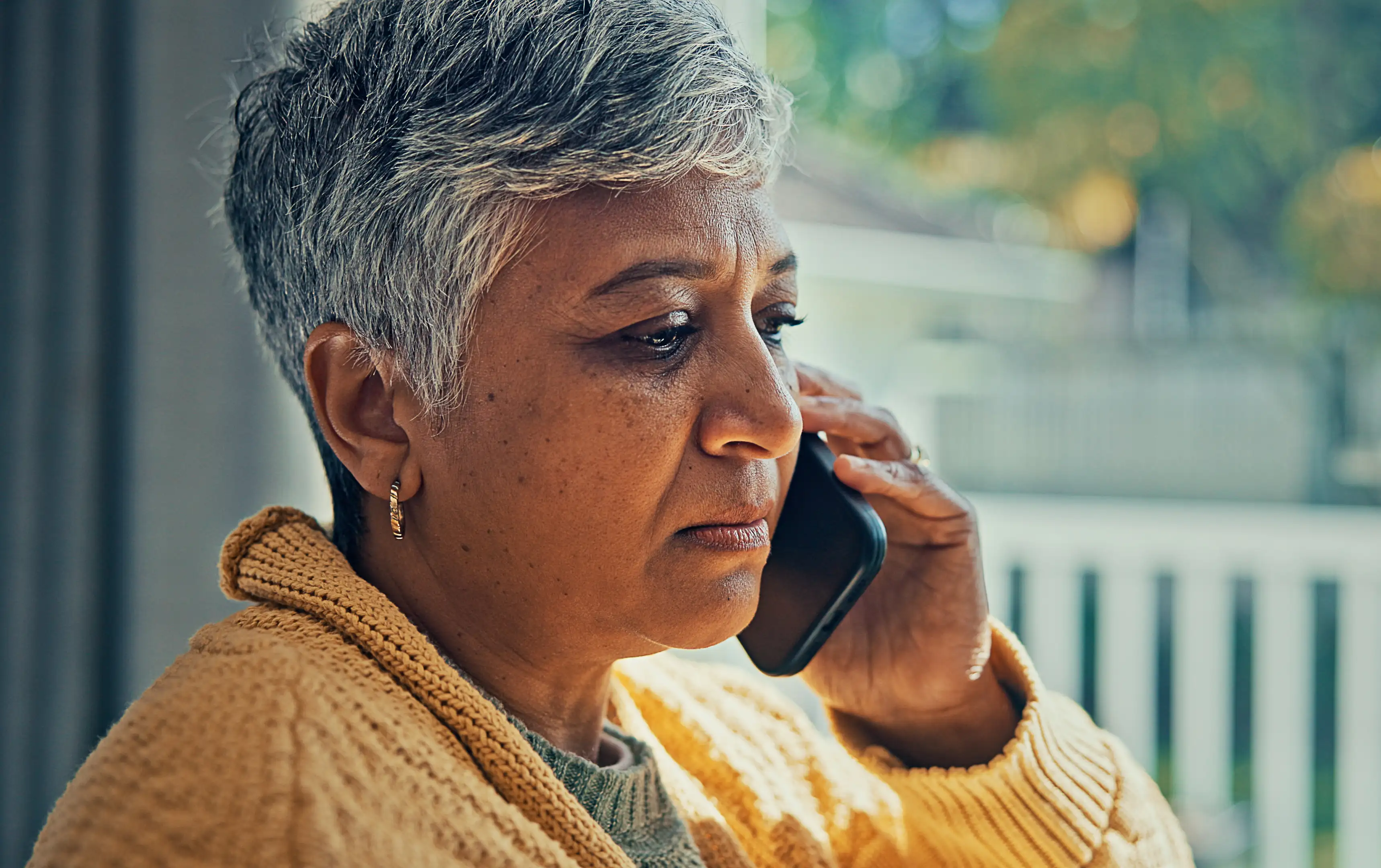 An older woman looking concerned while talking on the phone