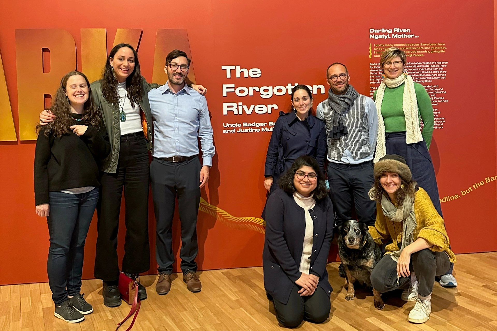 Group of people and one dog standing in front of an exhibition promotional wall decoration