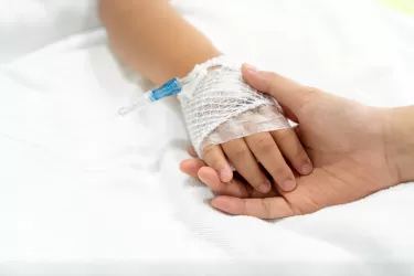 Child's hand with catheter holding adult hand 