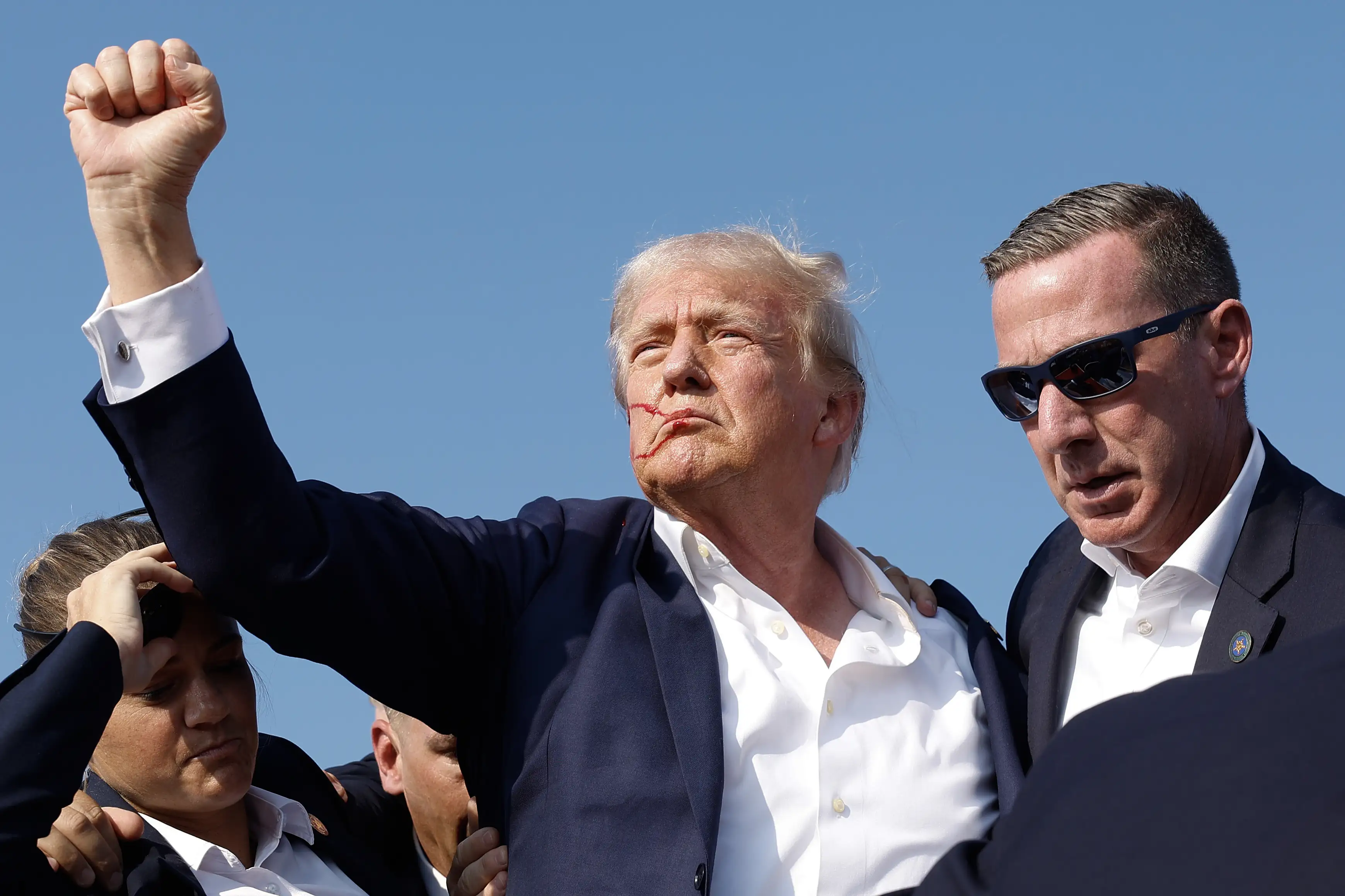 Donald Trump pumps his fist as he is rushed offstage after an attempted assassination