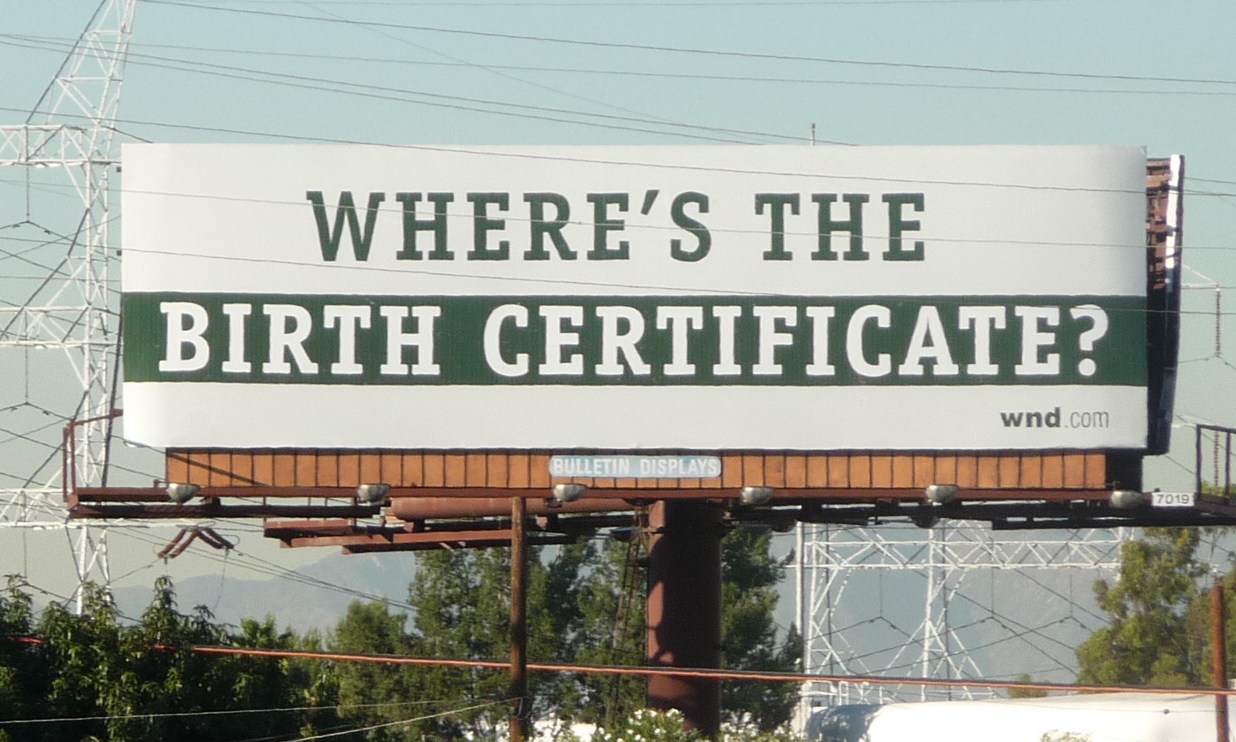 A billboard with the text 'WHERE'S THE BIRTH CERTIFICATE?'