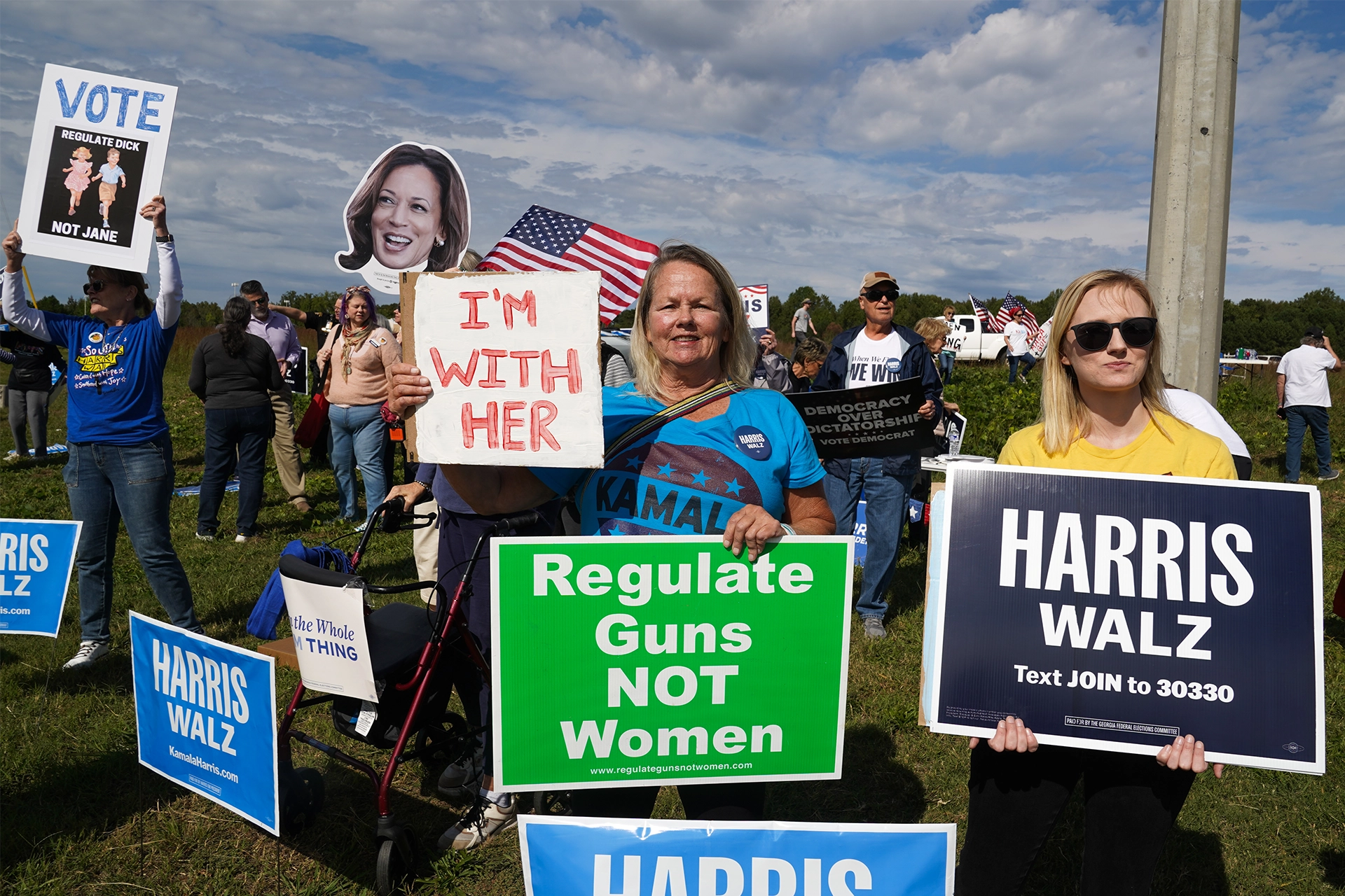 Group of women holding billboards supporting Kamala Harris by side of road