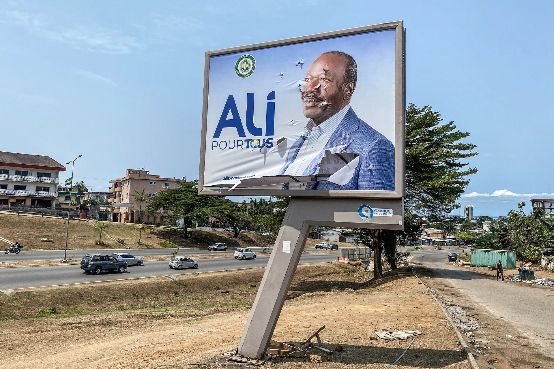 A roadside sign of Gabon President Ali with rips and bullet holes